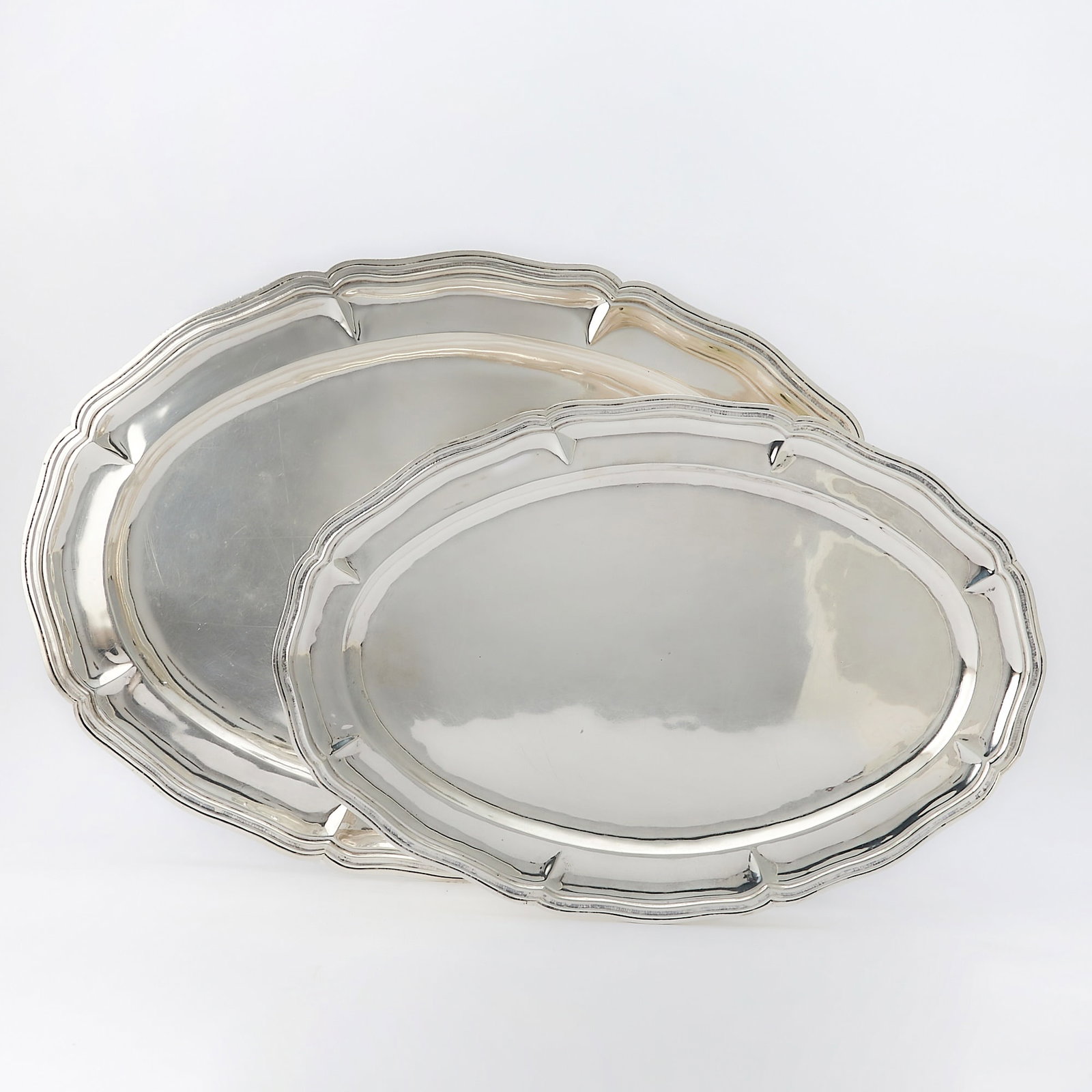 Pair of Mexican Sterling Silver Graduated Platters: Joyeria Real, mid 20th century Each shaped oval with molded rim. Lengths 21 3/4 inches and 18 inches, total approximately 100 ounces.