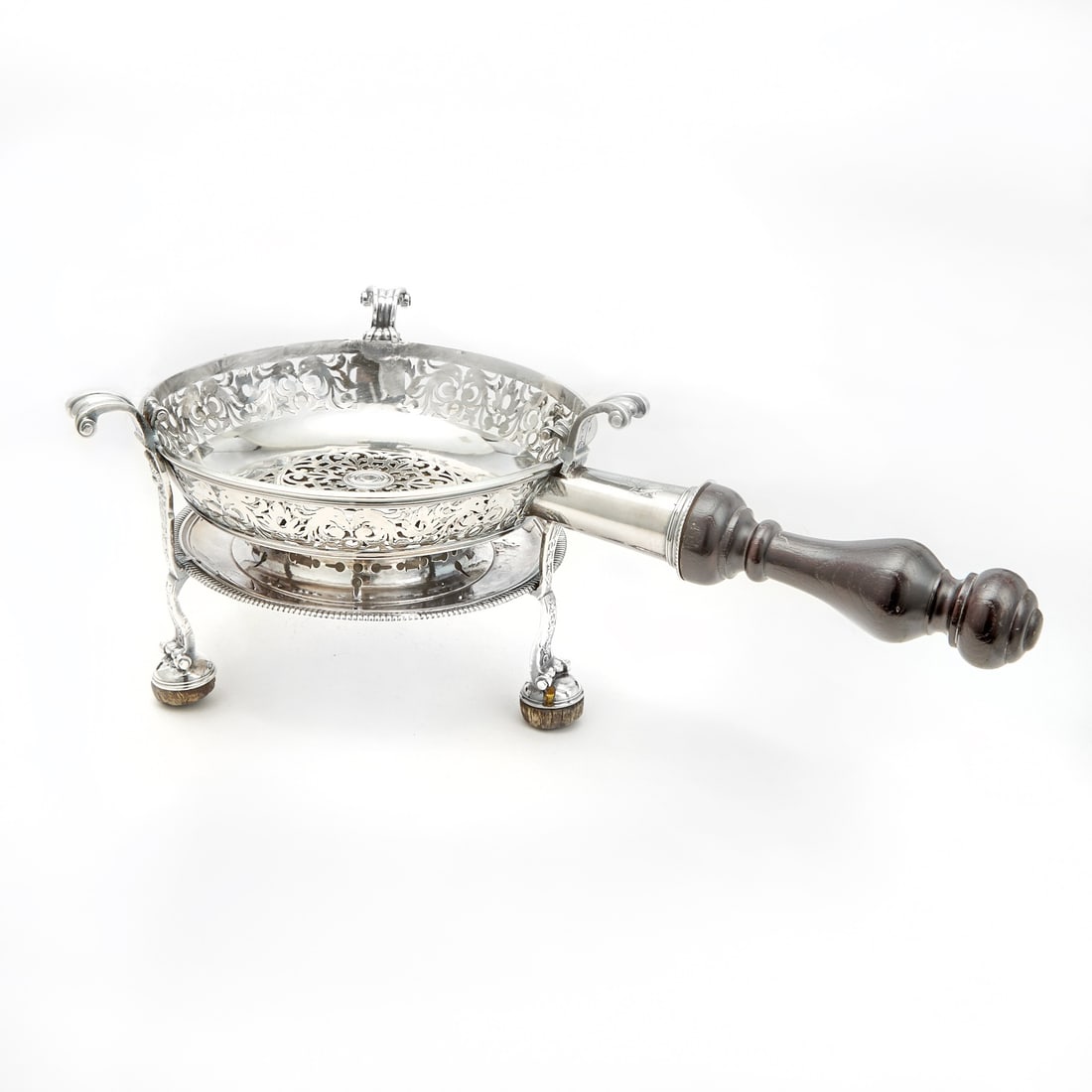 French Silver Braizer: The circular body pierced with band of stylized scrolls and masks, raised on three legs applied with strapwork, on bun feet. Height 6 1/2 inches (16.5 cm), length over handle 17 inches (43 cm), approx