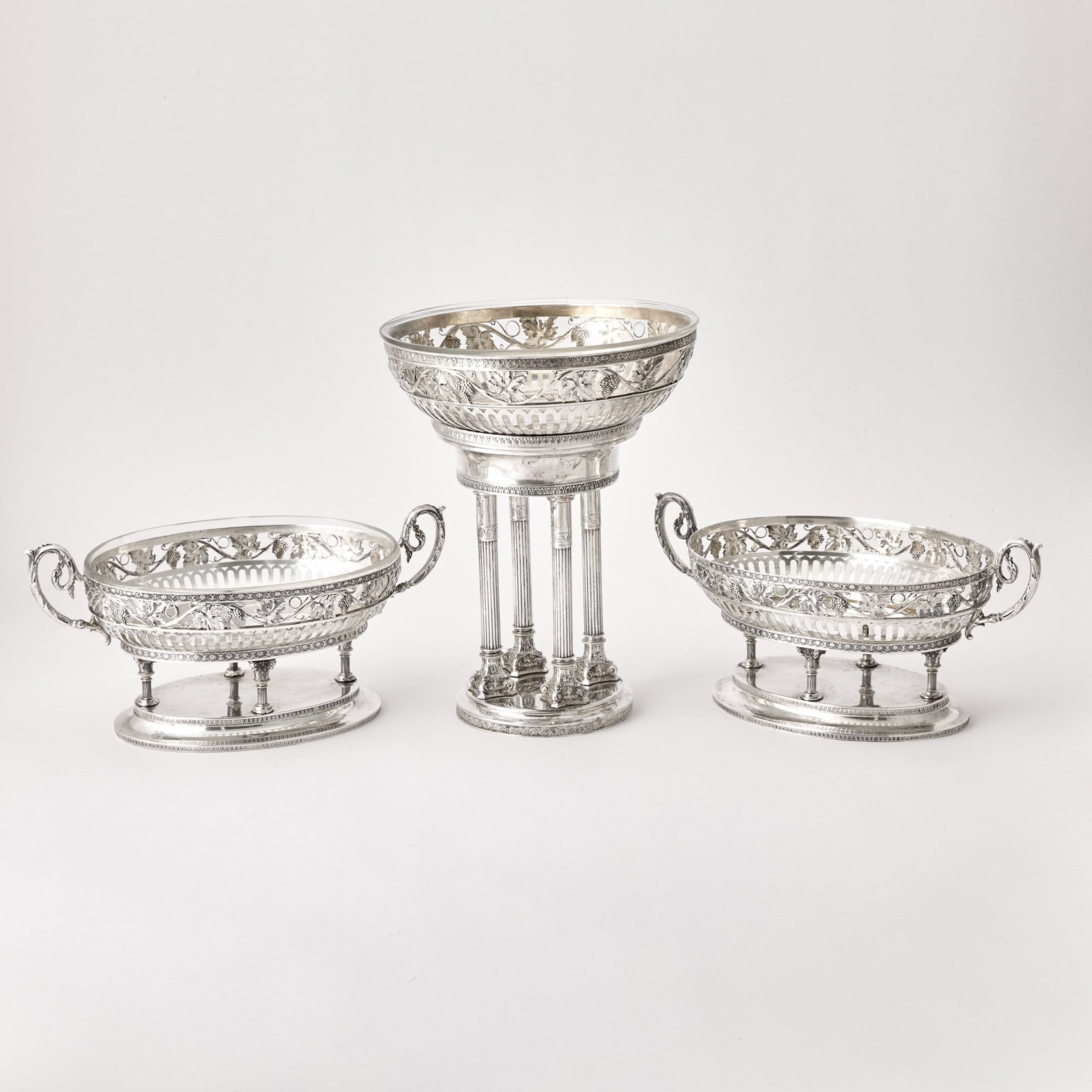 Austrian Silver and Glass Table Garniture: V. Mayer & Soehne, Vienna, early 20th century Comprising a larger central bowl and pair of smaller oval bowls, each with openwork band of grape clusters and vines, raised on reeded columnar suppor