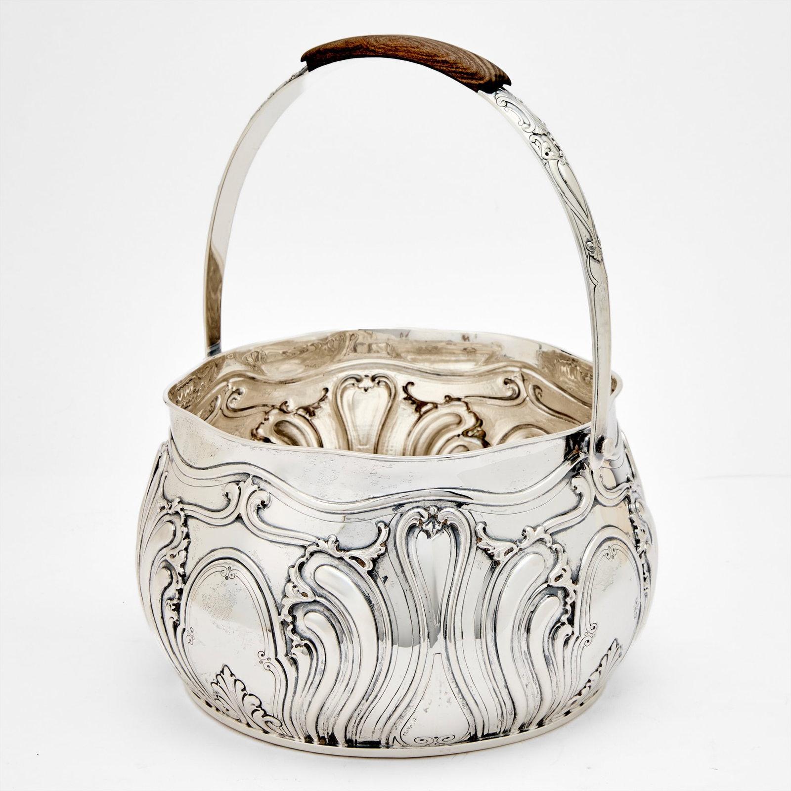 Italian Sterling Silver Centerpiece Basket: Mazzucato, Milan, late 20th century Circular chased with scrolls centering four cartouches, with an overhead swing handle. Height over handle 13 inches (33 cm), height of body 6 inches (15 cm), diamet