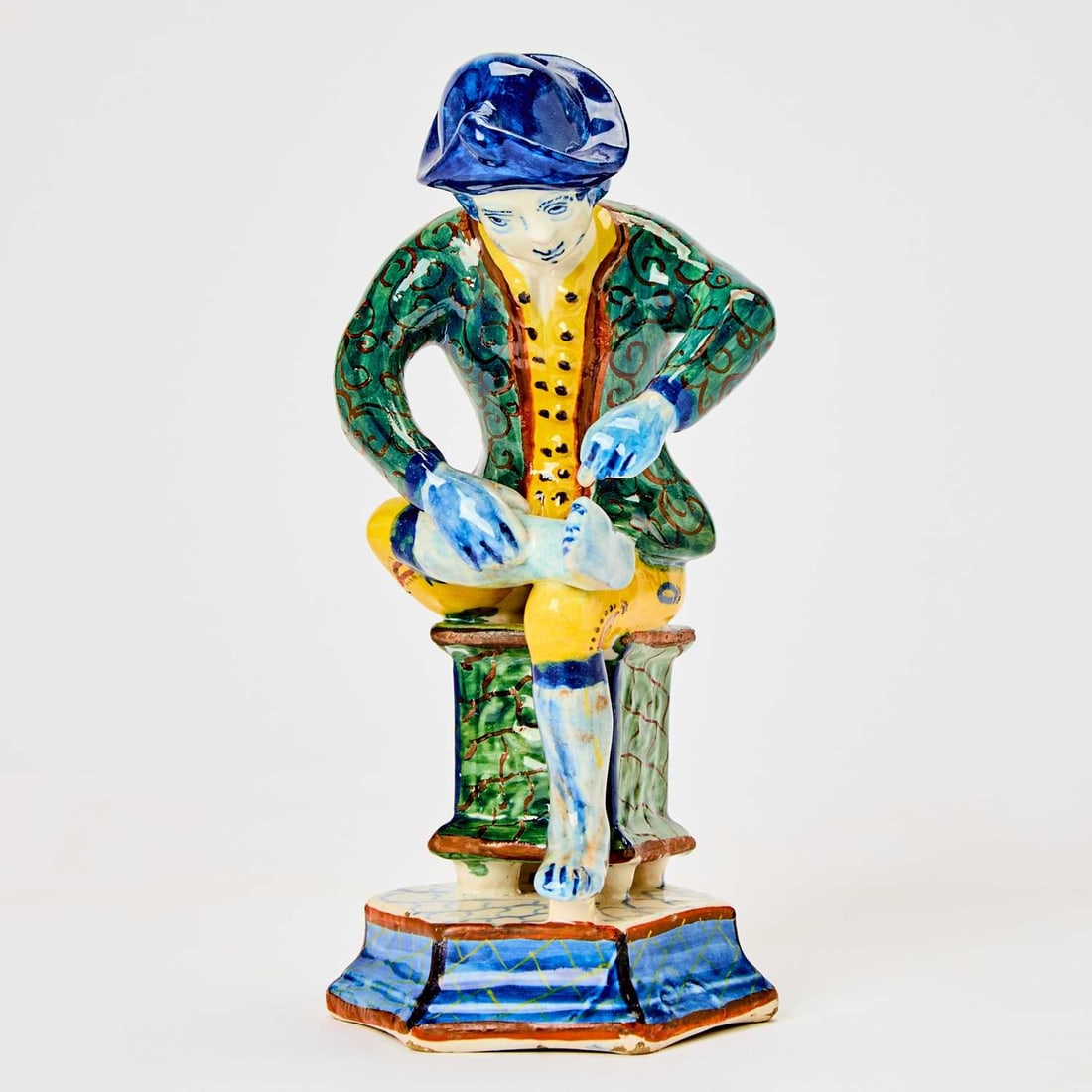 Dutch Delft Figure of 'Il Spinario': Circa 1740-60 The youth depicted in a blue hat with blue curly hair, green jacket and yellow breeches modeled seated pulling a thorn from his foot. Height 8 7/8 inches (22.5 cm). Provenance: Arnson An