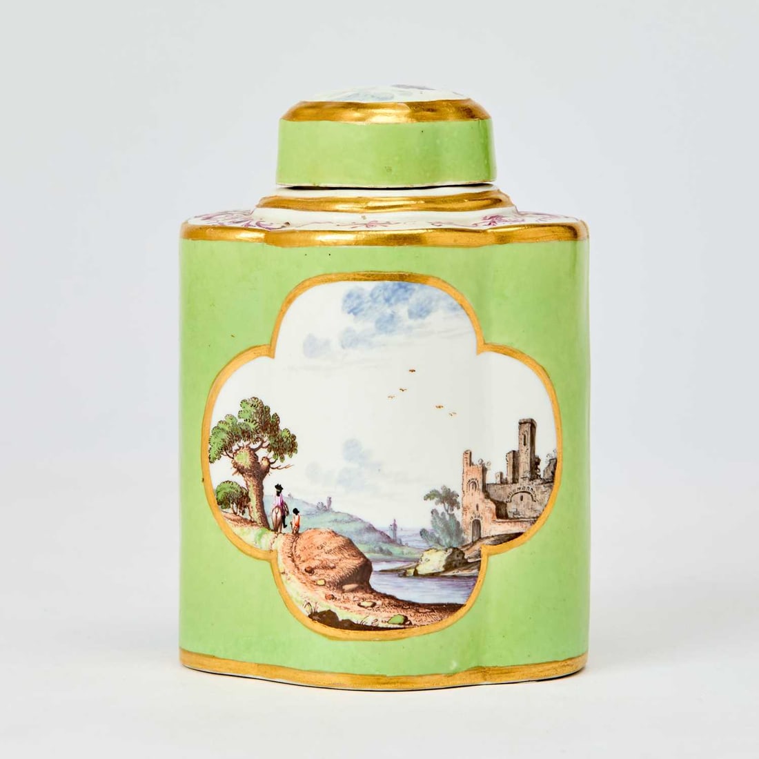 Meissen Lime-Green Ground Quatrefoil Tea Canister and Cover: Circa 1735 Reserved with gilt-lined quatrefoil cartouches of figures walking in a landscape below a conforming domed cover, further enriched with gilt, with blue crossed swords mark. Height 4 3/4 inch