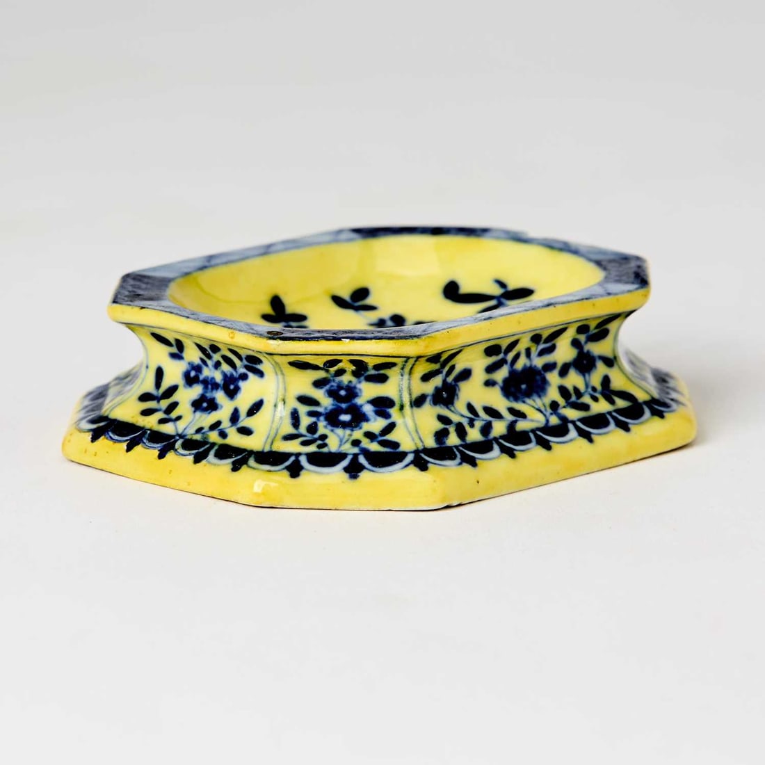Meissen Porcelain Pale Yellow Ground Salt: Circa 1740 Of oblong octagonal form, painted in blue, the basin with a spray of Indianische Blumen within a blue and white zig-zag border, the sides with similar flowers above a scalloped