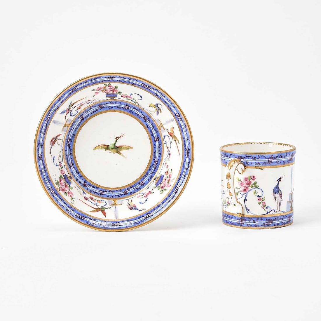 Sèvres Cup and Saucer (Gobelet Litron et à Soucoupe): Circa 1786 Painted with avian species in flight and urns of flowers between narrow blue bands and carmine scrolls, with blue interlaced L's enclosing date letters II, painter's mark for Denis Levé