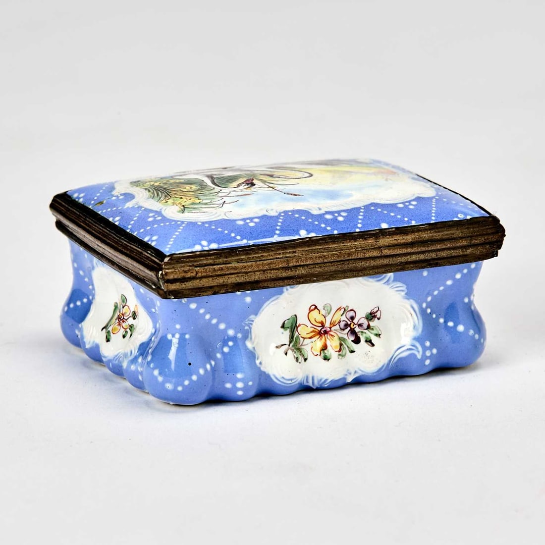 Staffordshire Copper-Mounted Enamel Blue-Ground Snuffbox and Cover: Circa 1780 The hinged cover painted with swimming swans on a white ground within a blue-ground border further 'jeweled' with white enamel, the sides reserved with panels of flowers. Width 2 1/2 inches