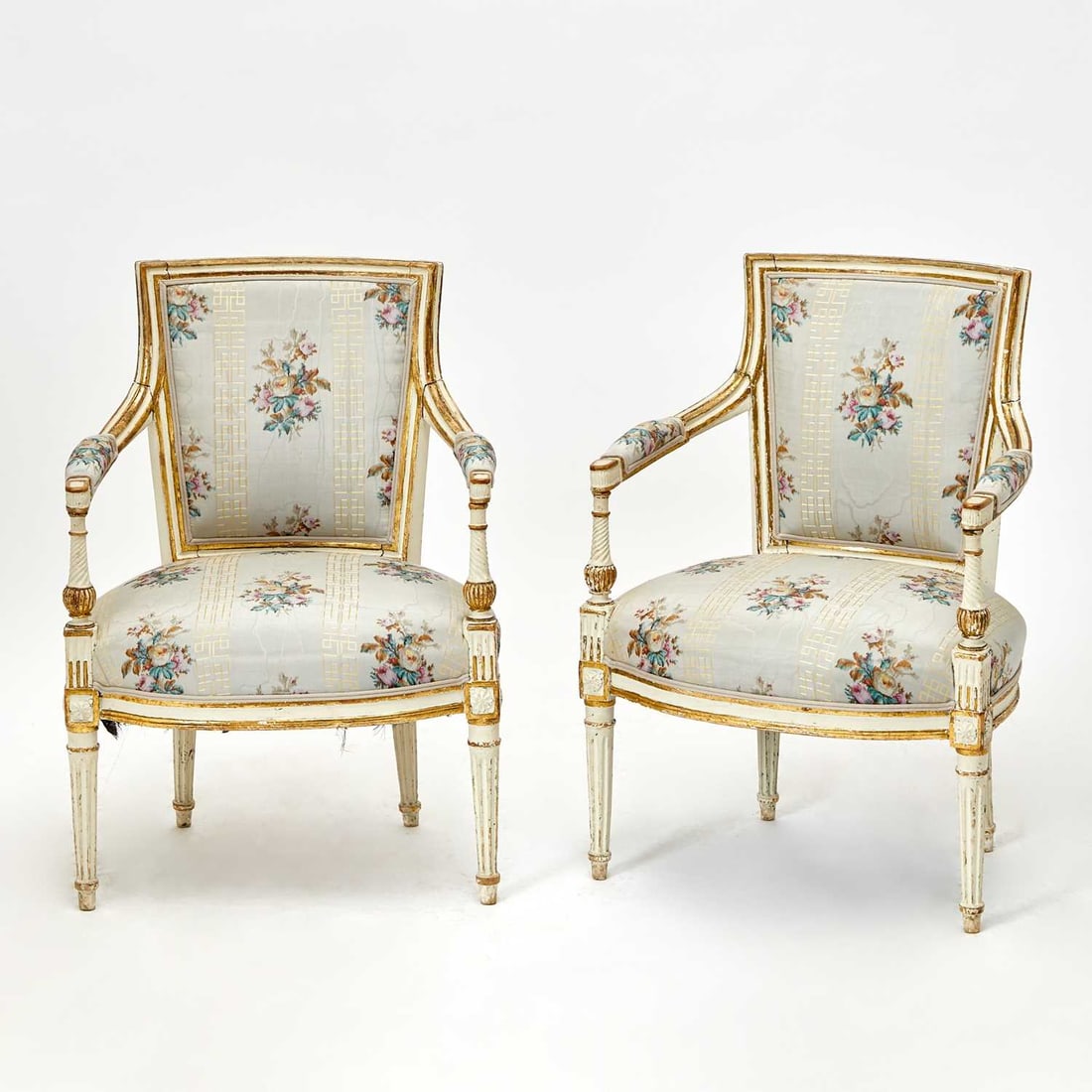 Pair of Louis XVI Painted and Parcel-Gilt Fauteuils en Cabriolet: Last quarter 18th century Each slightly curved padded back and arms over a serpentine seat, with fluted baluster-turned arm supports on tapering fluted legs. Height 32 inches (81.3 cm), width 22 1/2 i