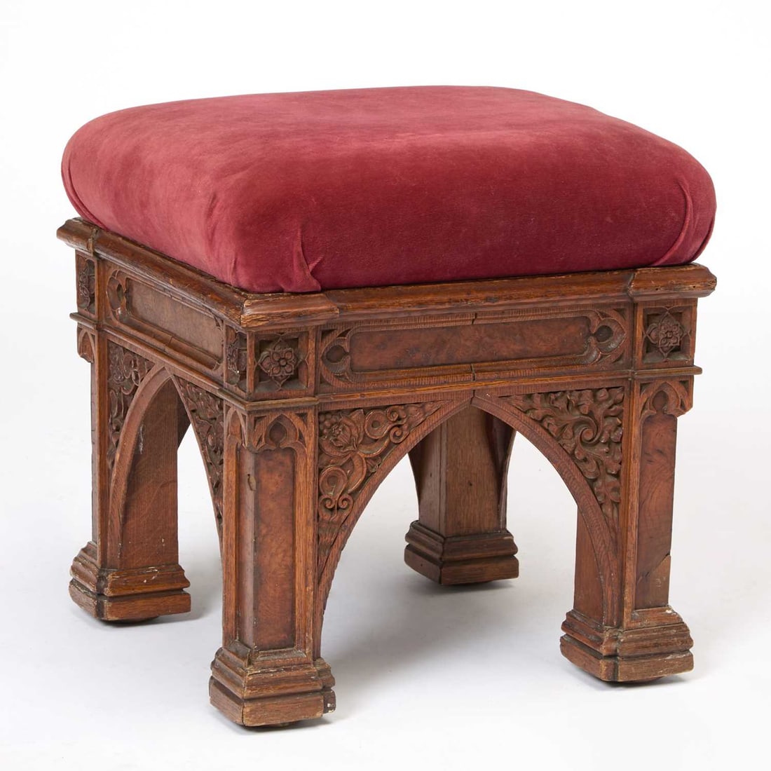 George IV Carved and Pollard Oak Stool: Morel and Seddon, circa 1827-28, the design attributed to A.W. N. Pugin The square red velvet upholstered cushion above a blind tracery and pollard oak-veneered base, the underside of the seat cushion