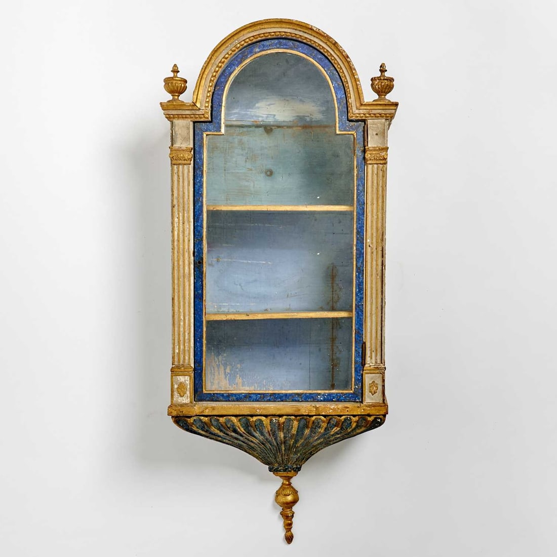 Italian Neoclassical Painted and Giltwood Reliquary Corniche: Late 18th century The arched case with glazed door and with molded surround with gilt rosettes and reeded plasters, the blue ground flanked by gilt finials, the interior fitted with shelve