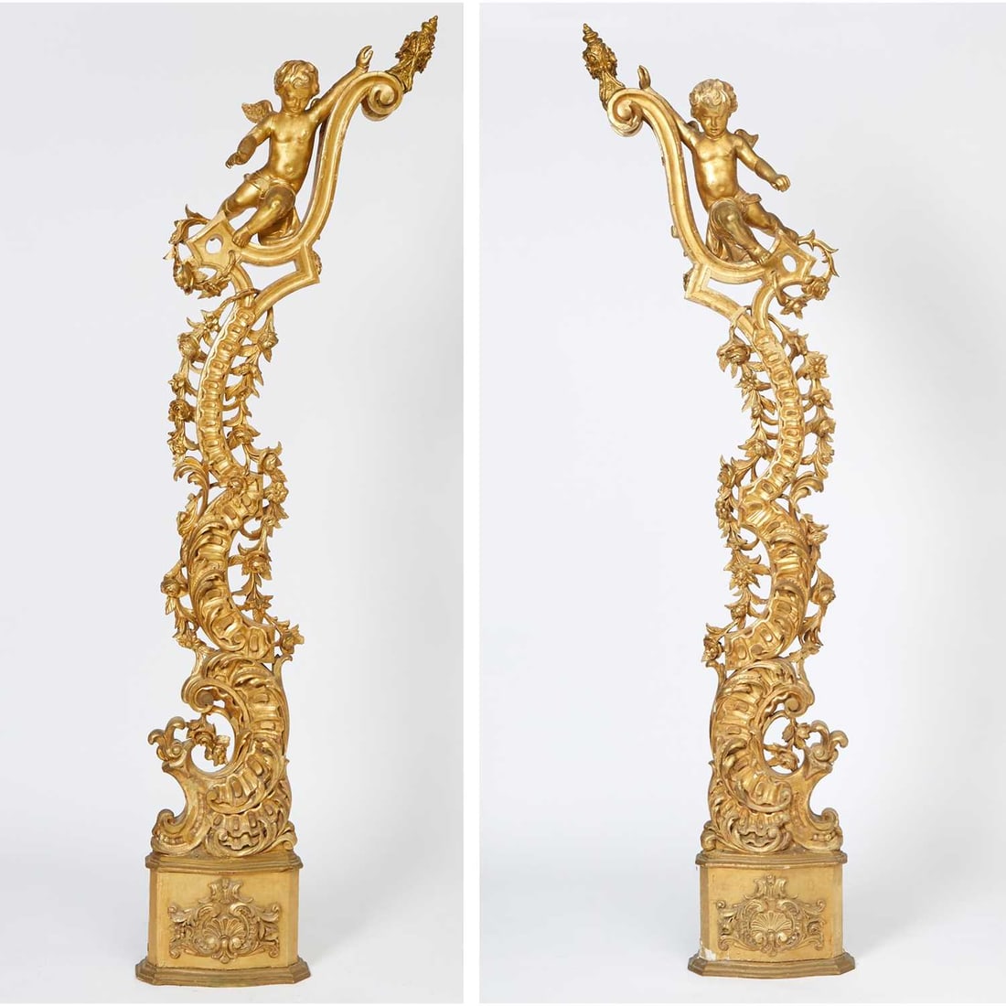 Pair of Italian Rococo Style Carved Giltwood Putti Columns: Circa 1860 Each modeled in the round, issuing from an acanthus and foliate framework; the whole forming a vertical cascade of pierced and carved C-scrolls, rocailles, and trailing foliage surmounted b