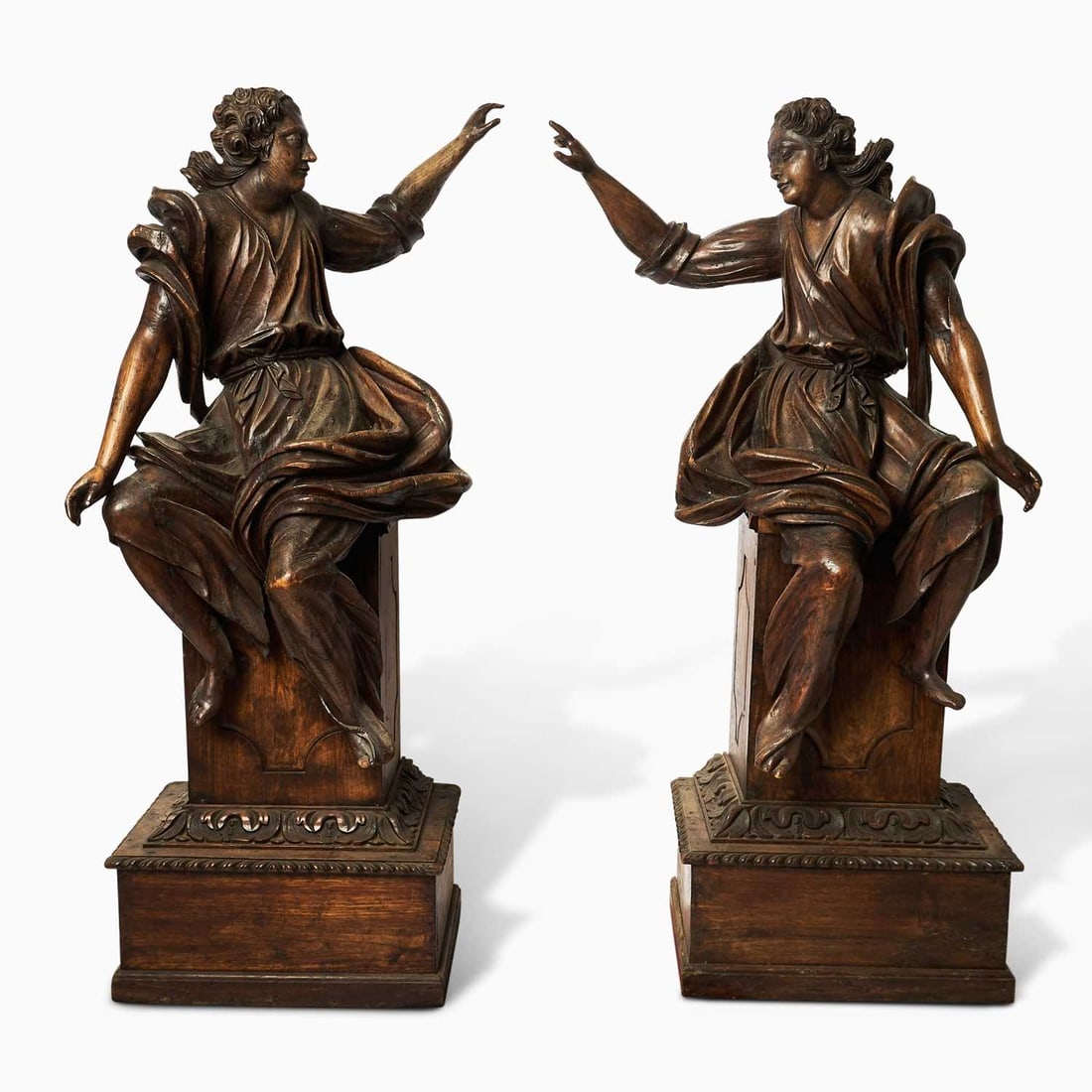 Pair of Dutch Baroque Carved Oak Figures of Seated Angels: 18th Century Each figure carved in the round, the torsos twisting and the drapery with fluid folds; the faces with full cheeks and curling hair, the arms extended outward in lively gesture; on later p