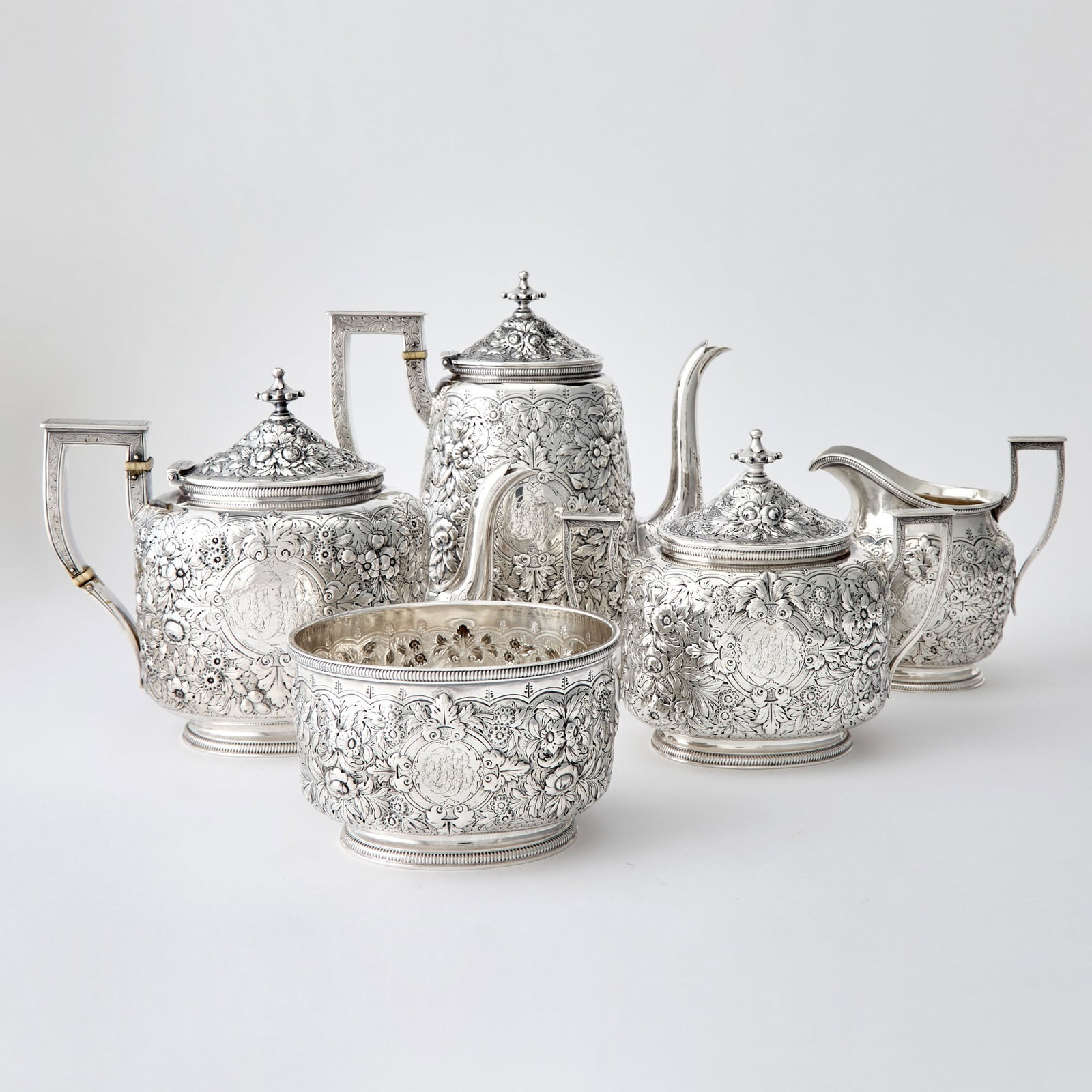 Bigelow, Kennard & Co. Sterling Silver Tea and Coffee Service: Boston, third quarter 19th century Each chased overall with foliate scrolls, comprising a teapot, coffee pot, height 8 3/4 inches, cream jug, covered sugar bowl and a waste bowl. Total approximately