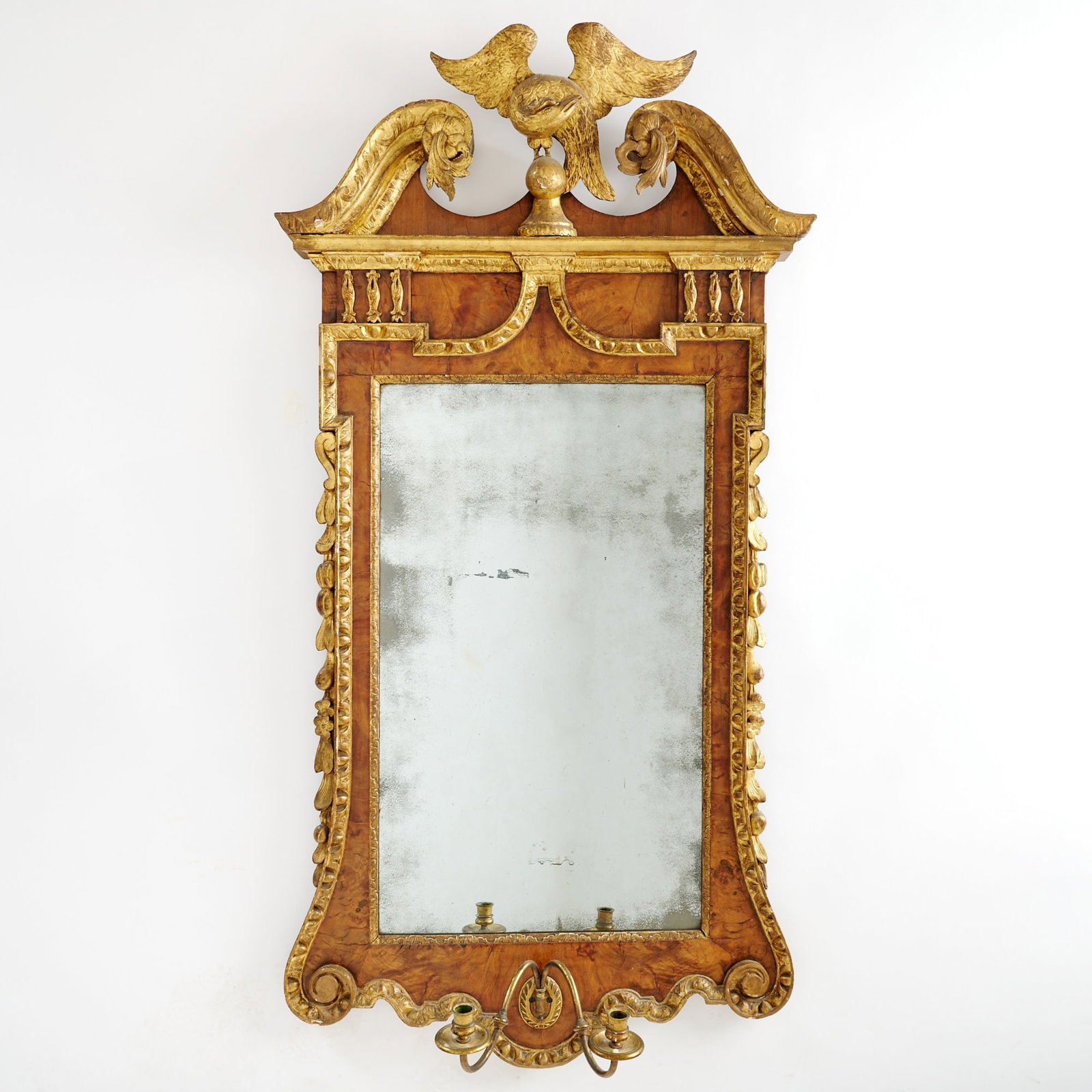 Mahogany and Burlwood Parcel-Gilt Mirror: Probably England, late 18th century With scrolled pediment centering a spreadwing eagle finial, above a mirror glass with gilt liner flanked by molded, scrolled, and leaf-carved sides, all above a