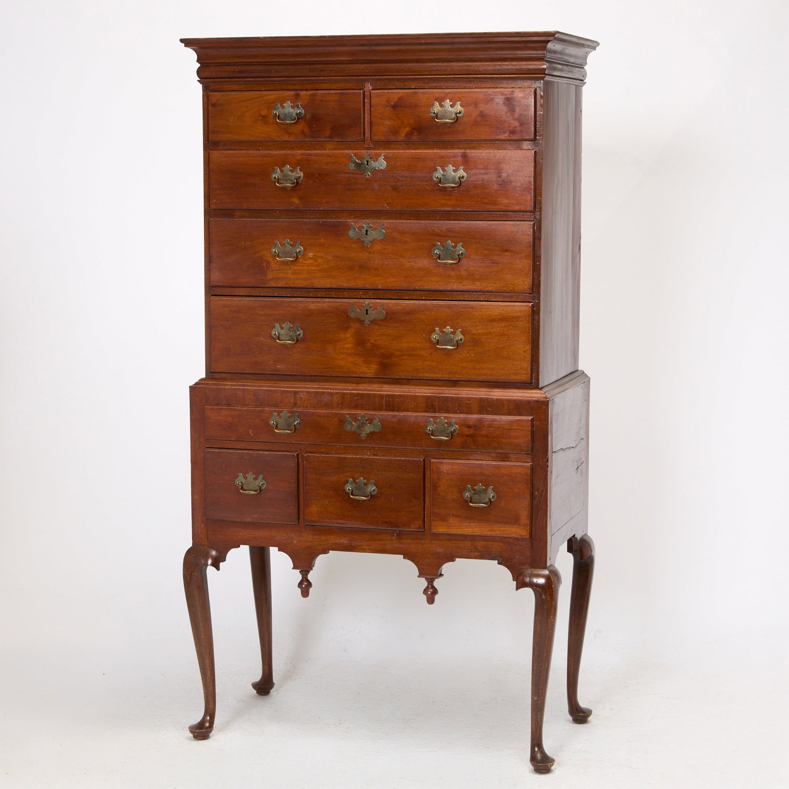 Queen Anne Walnut and Maple High Chest of Drawers: Eastern Massachusetts, circa 1765 The molded cornice above two short and three long thumbmolded graduated drawers on lower section of single long drawer and three short drawers above a valanced apron