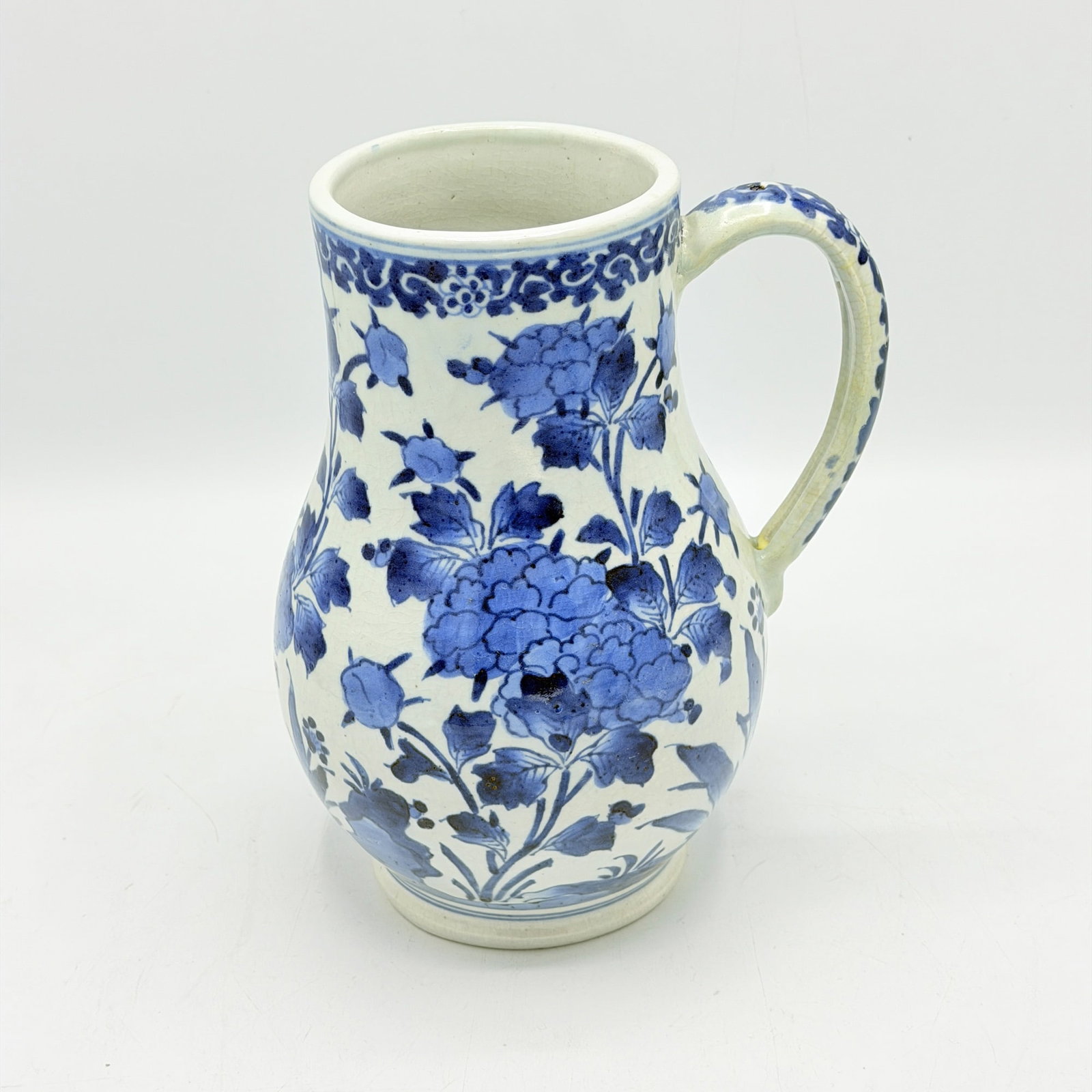 Japanese Blue and White Porcelain Jug Edo Period: The bulbous body rising from a short foot to a slightly flared rim, decorated with peony blossoms and buds borne on leafy branches emerging from rockwork. Height 9 inches.