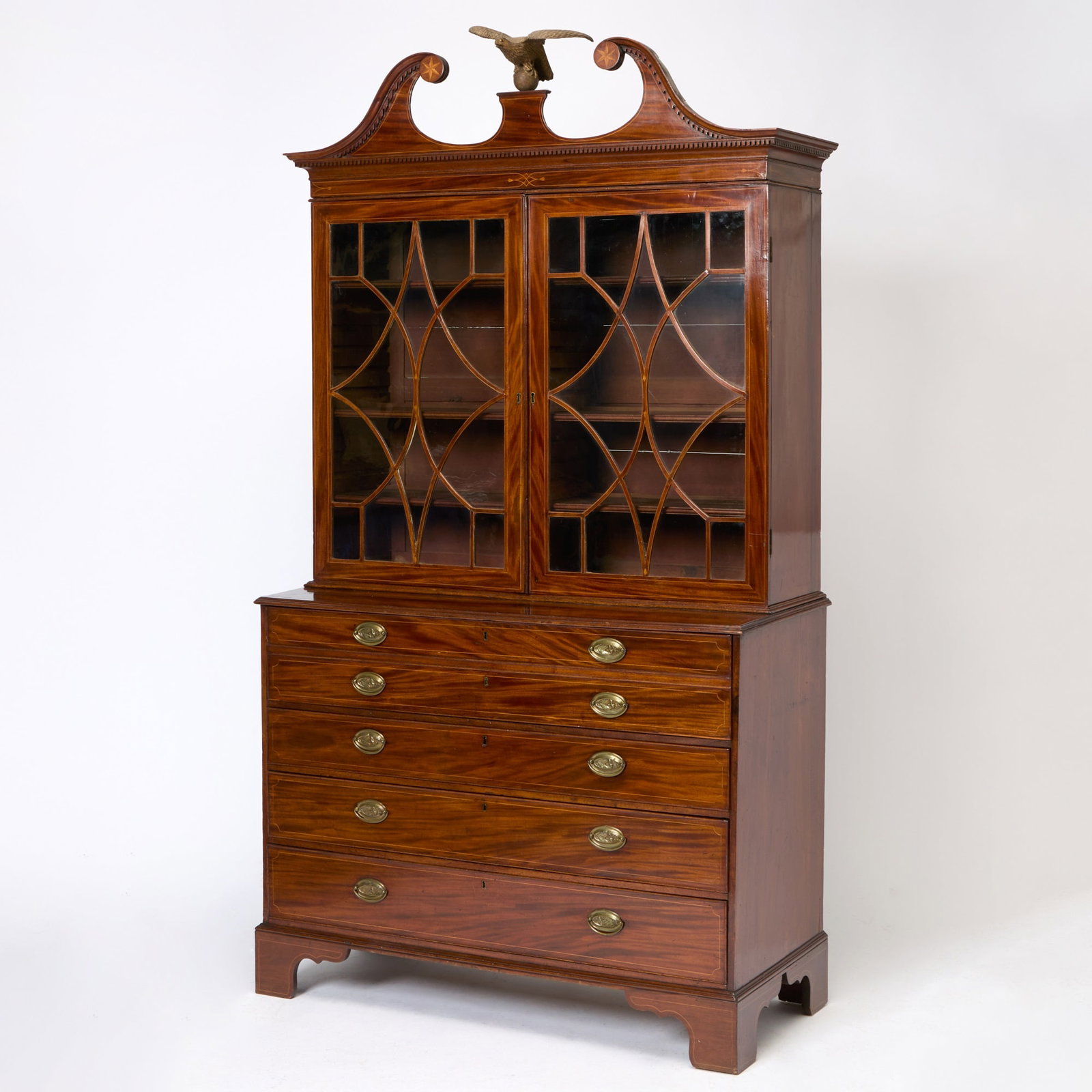 Federal Inlaid Mahogany Desk and Bookcase: Baltimore, Maryland, circa 1810 The upper section with removable scrolled and arched pediment centering an eagle, above glazed doors opening the shelves, the lower section with hinged writing surface