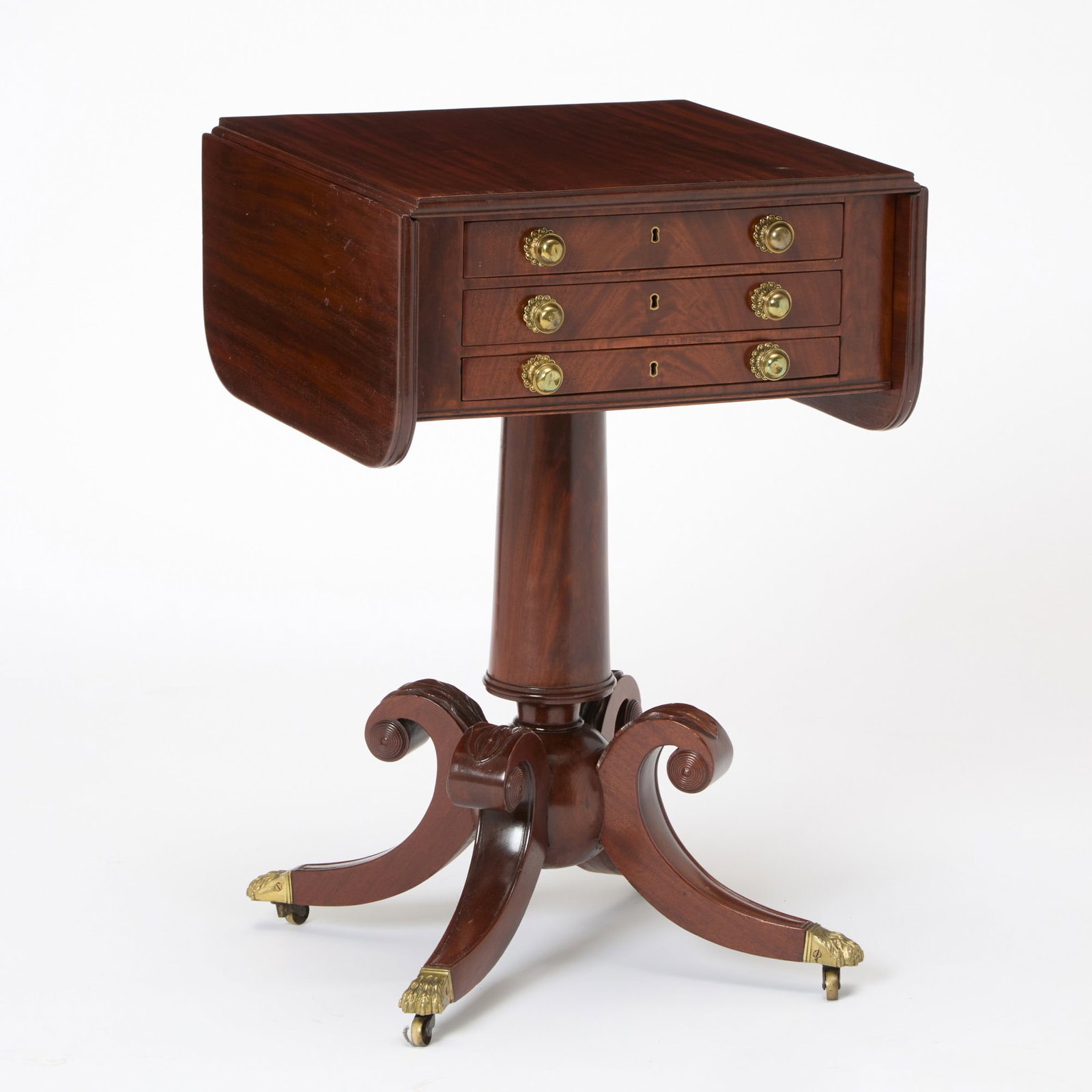 Classical Mahogany Three Drawer Work Table: Probably Boston, circa 1820 The top two drawers fitted, raised on columnar post terminating at a ball issuing four scrolled leaf-carved molded legs with brass hairy-paw cap casters. Height 29 inches,