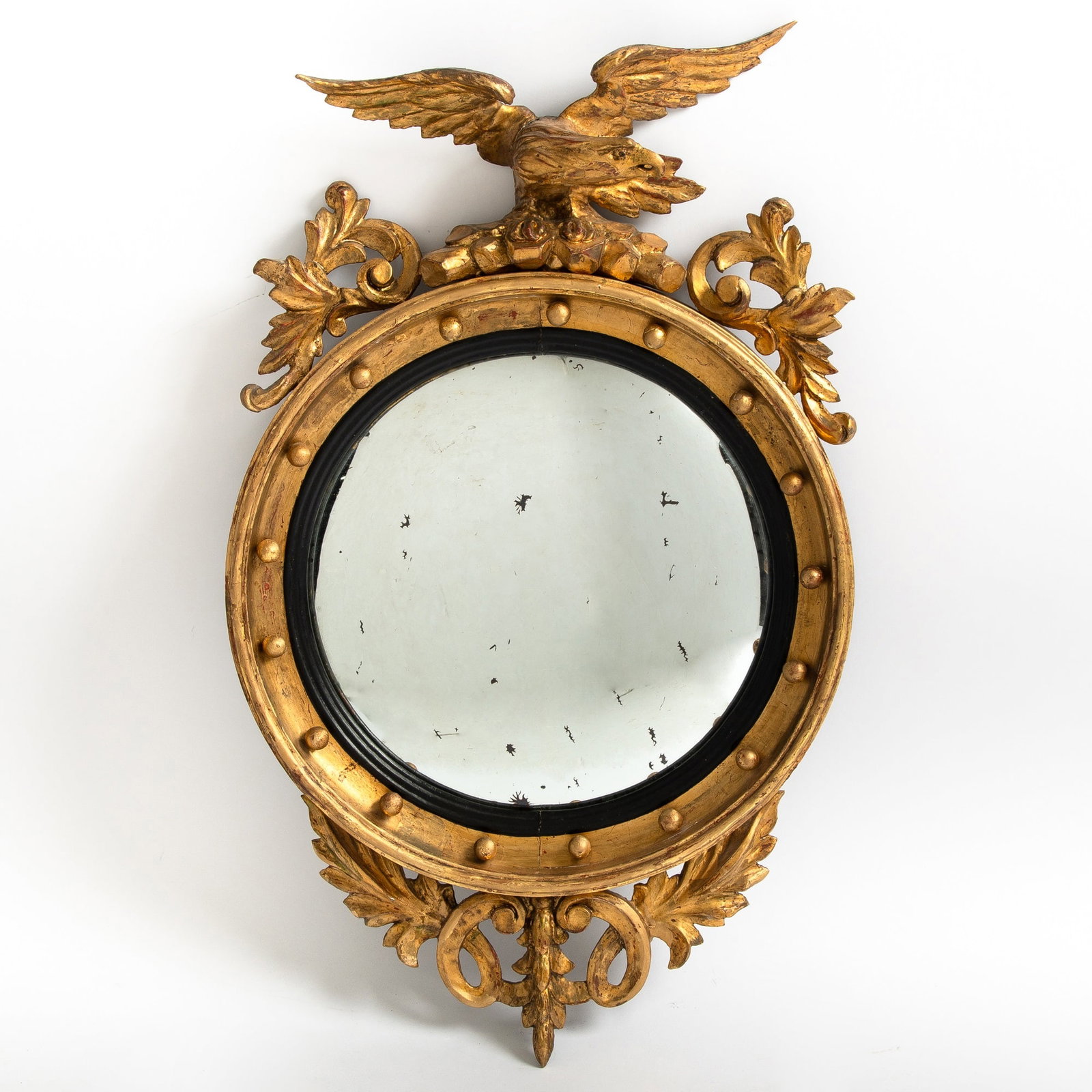 Classical Giltwood Girandole Mirror: America or England, early 19th century The circular frame with spherules, reeded ebonized liner, and convex glass all surmounted by a spreadwing eagle perched on rockery. Height 32 1/2 inches, frame