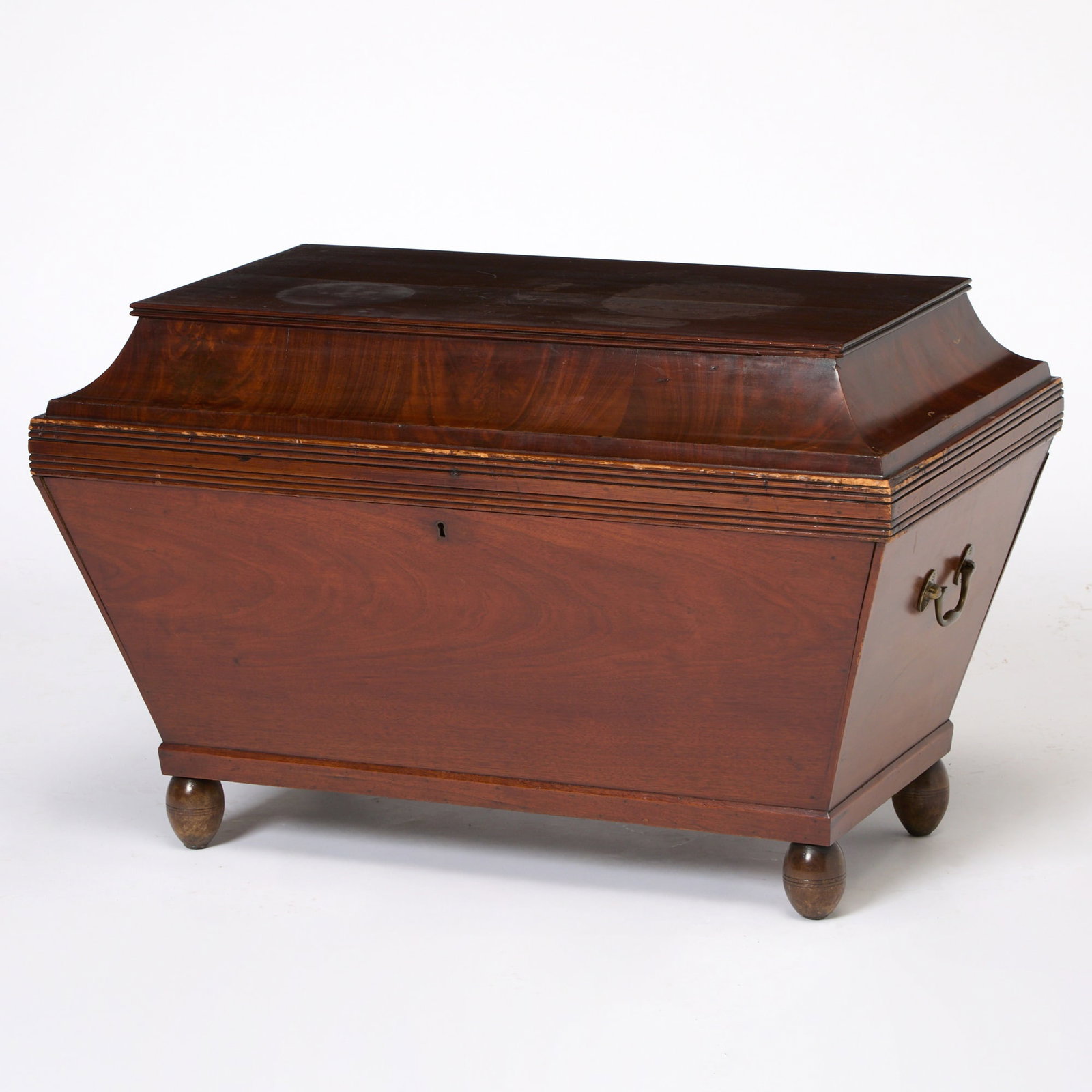 Classical Figured Mahogany Cellarette: New York or Boston, circa 1815 The hinged top with concave molding opens above a divided interior and canted case raised on turned feet. Height 21 inches, width 33 inches, depth 20 inches