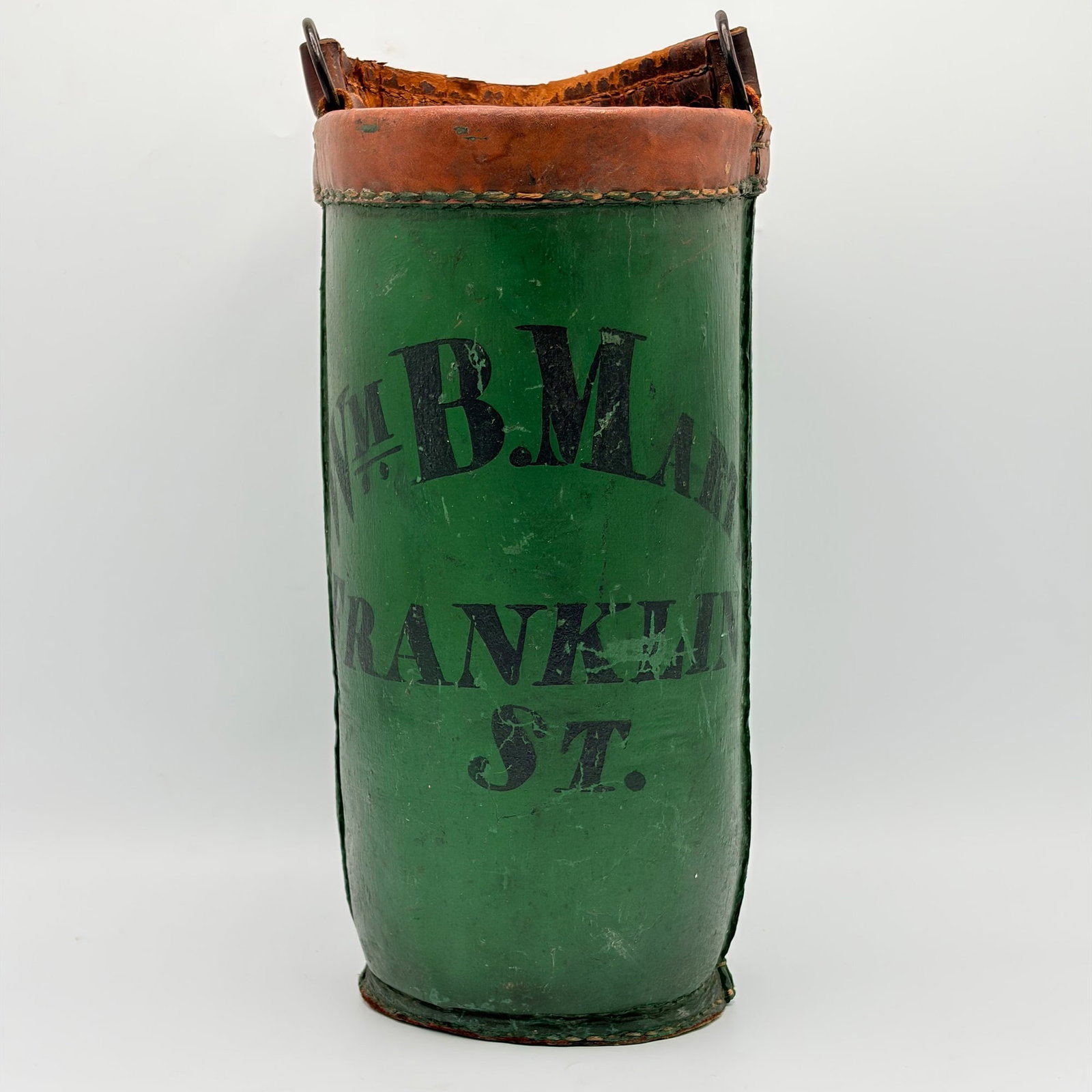 Green-painted Leather Fire Bucket: New England, early 19th century The leather swing handle on iron rings, above the green-painted body with black block letters "Wm. B. Martin/Franklin/St." Height including handle 19 inches.