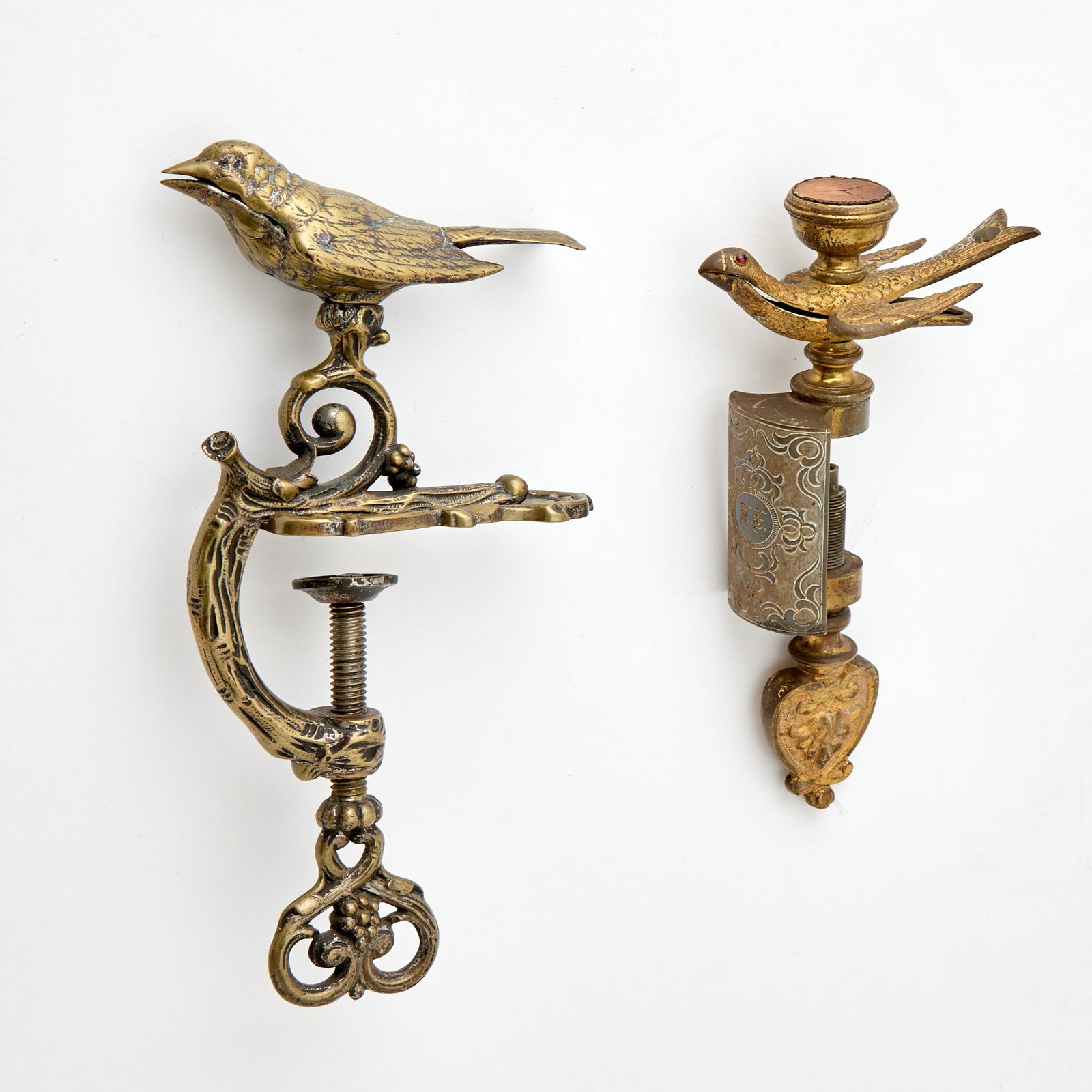 Two Brass Bird Sewing Clamps: Late 19th century Comprising a gilt example with jeweled eyes, height 7 1/2 inches; and an example with branch form clamp, height 8 1/4 inches.