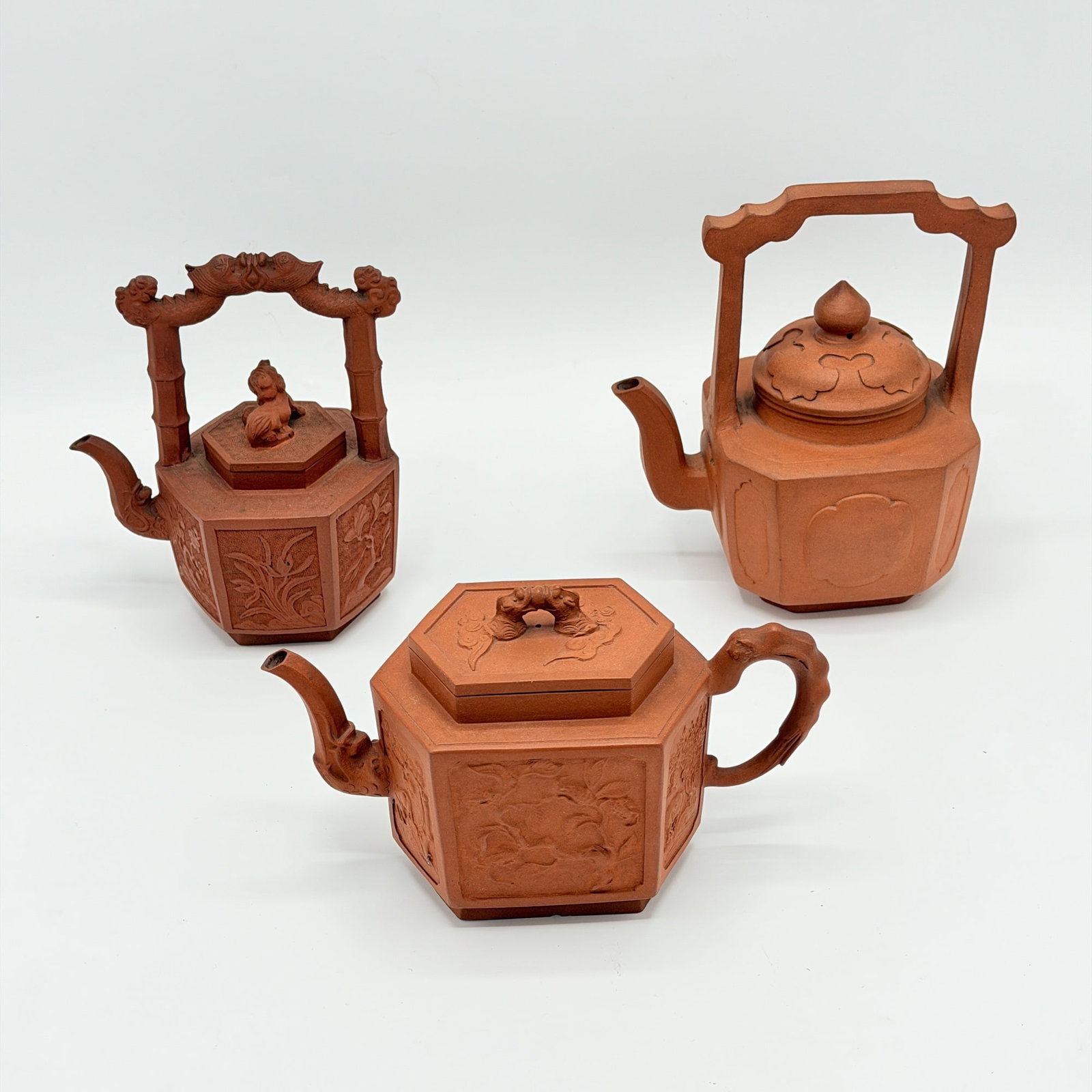 Group of Three Staffordshire Redware Teapots: England, late 18th century Each with paneled chinoiserie designs. Height of tallest to top of handle 6 3/4 inches.