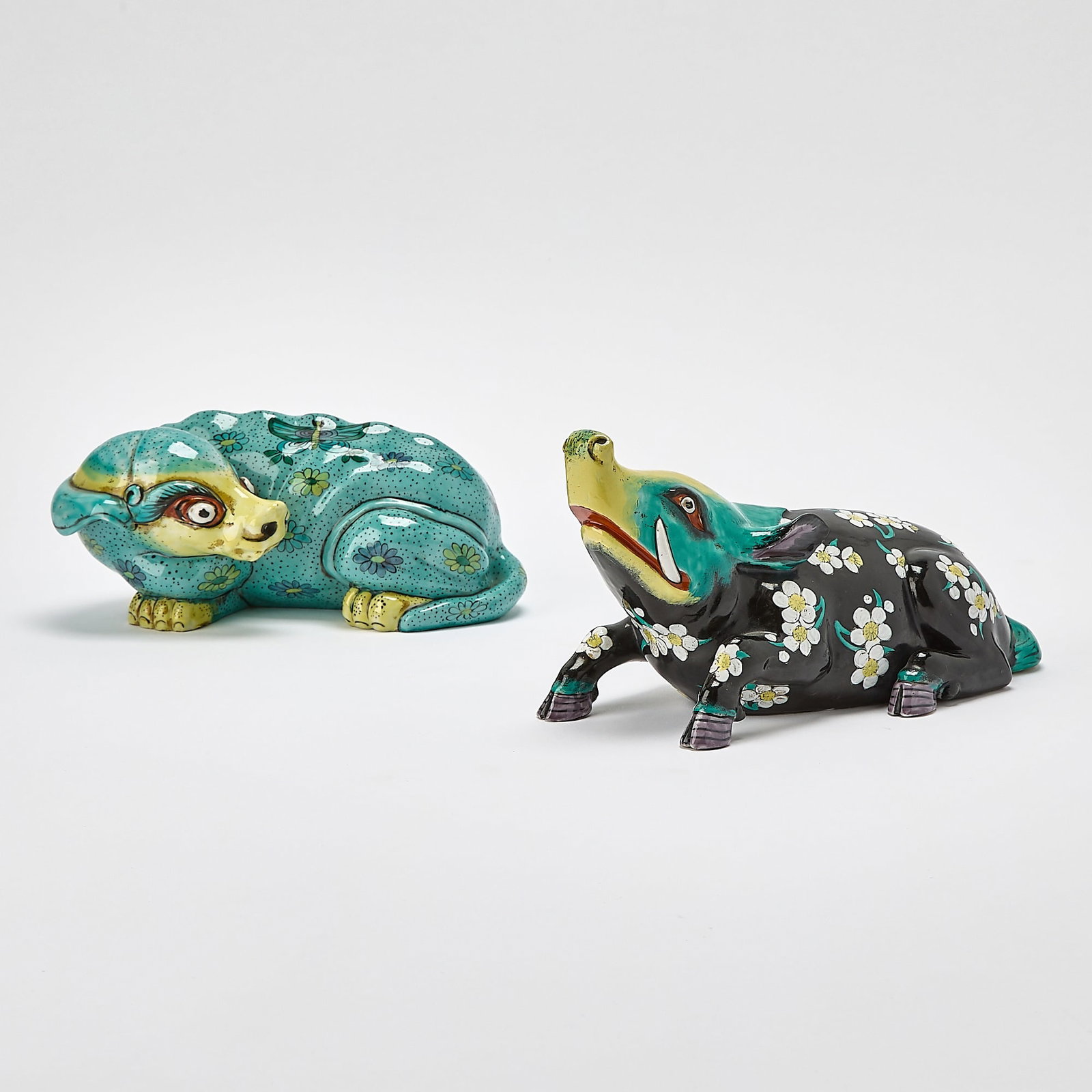 Two Porcelaine de Paris Hand-Painted Porcelain Animals in the Chinese Taste: Each figure modeled in a recumbent pose and with floral decoration, including a wild boar, retailed by Cartier,