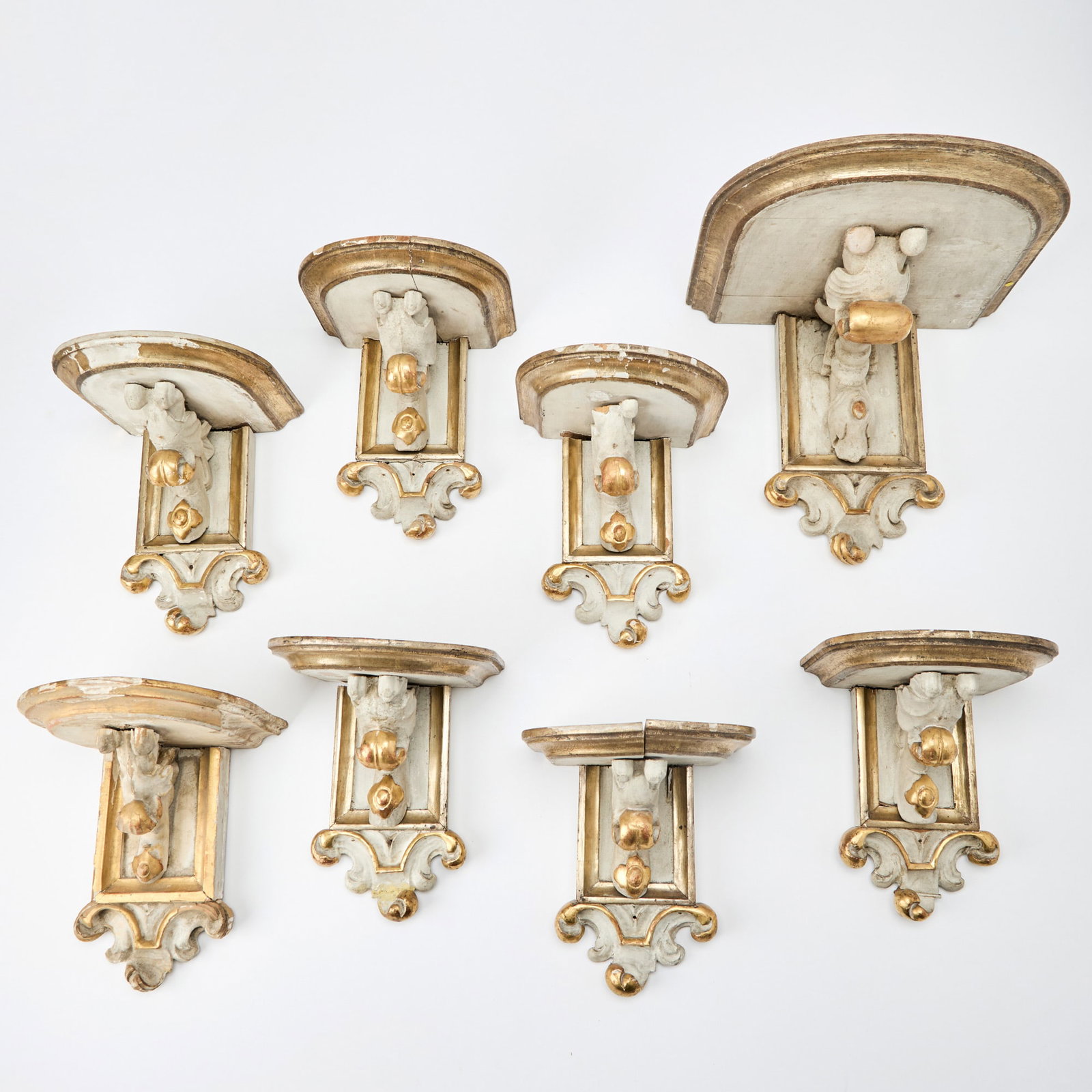 Group of Eight Baroque Style White Painted and Gilt Brackets: Height of largest 9 inches, width 10 1/2 inches, depth 9 3/4 inches; height of set of seven 7 1/2 inches, width 6 1/2 inches.