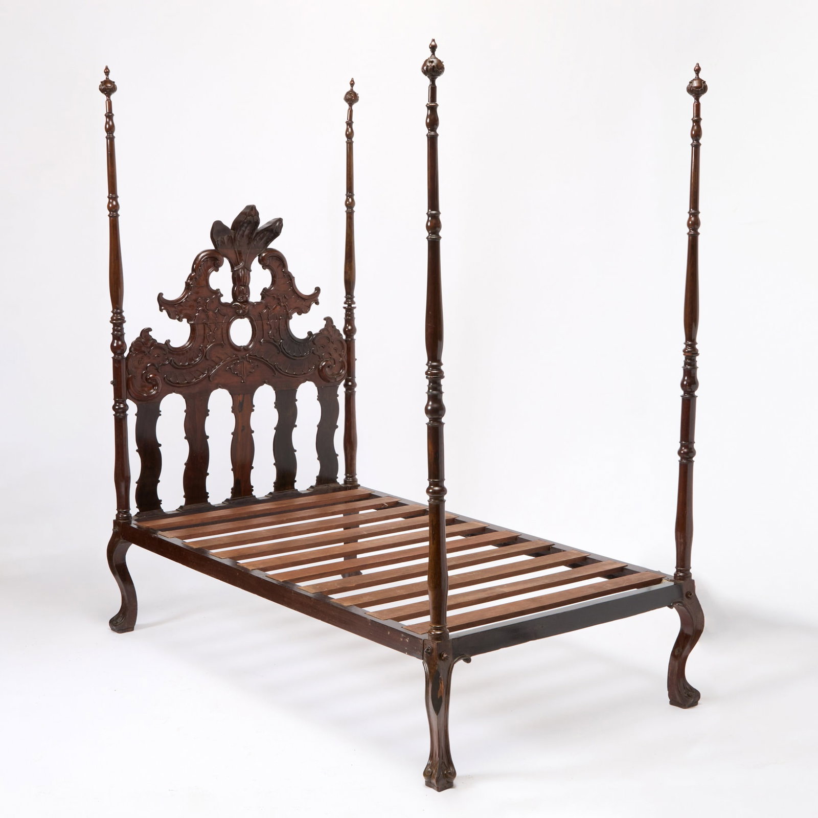 Portuguese Rococo Carved Jacaranda Four-Post Bedstead: 18th/19th century The headboard with a central foliate plume flanked by boldly-carved opposed scrolls over undulating vertical supports, the torsade posts with urn-form finials, raised on cabriole leg