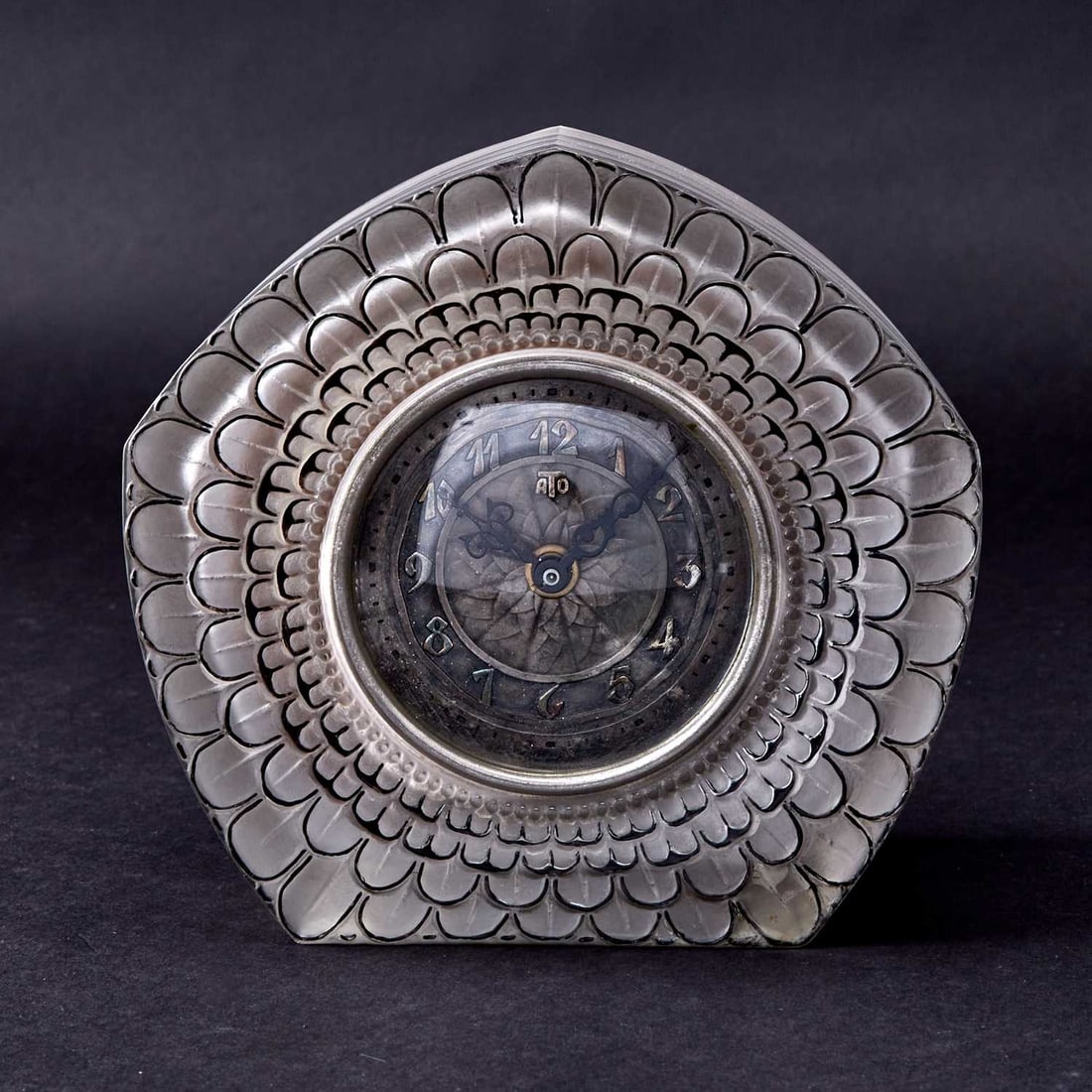 R. Lalique for ATO Molded and Enameled Glass"Dahlia" Mantel Clock: Model introduced 1924 Of arched form, in transparent light gray colored glass, the front molded with a large stylized dahlia blossom, in intaglio relief, heightened in black enamel, the circular dial 