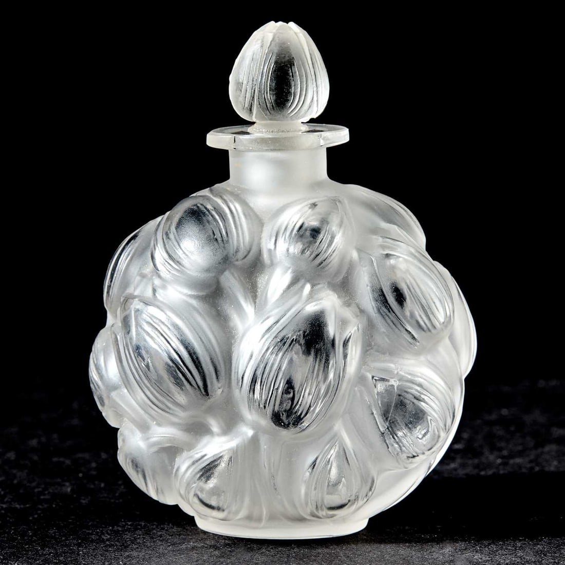 R. Lalique Molded Glass "Marchant Mais Charmont" Perfume Bottle and Stopper: Model introduced 1927 In colorless glass, the body molded with stylized tulip blossoms in protruding relief, satin and glossy finish, conforming bud-form stopper, molded FRANCE and R. LALIQUE. Height 