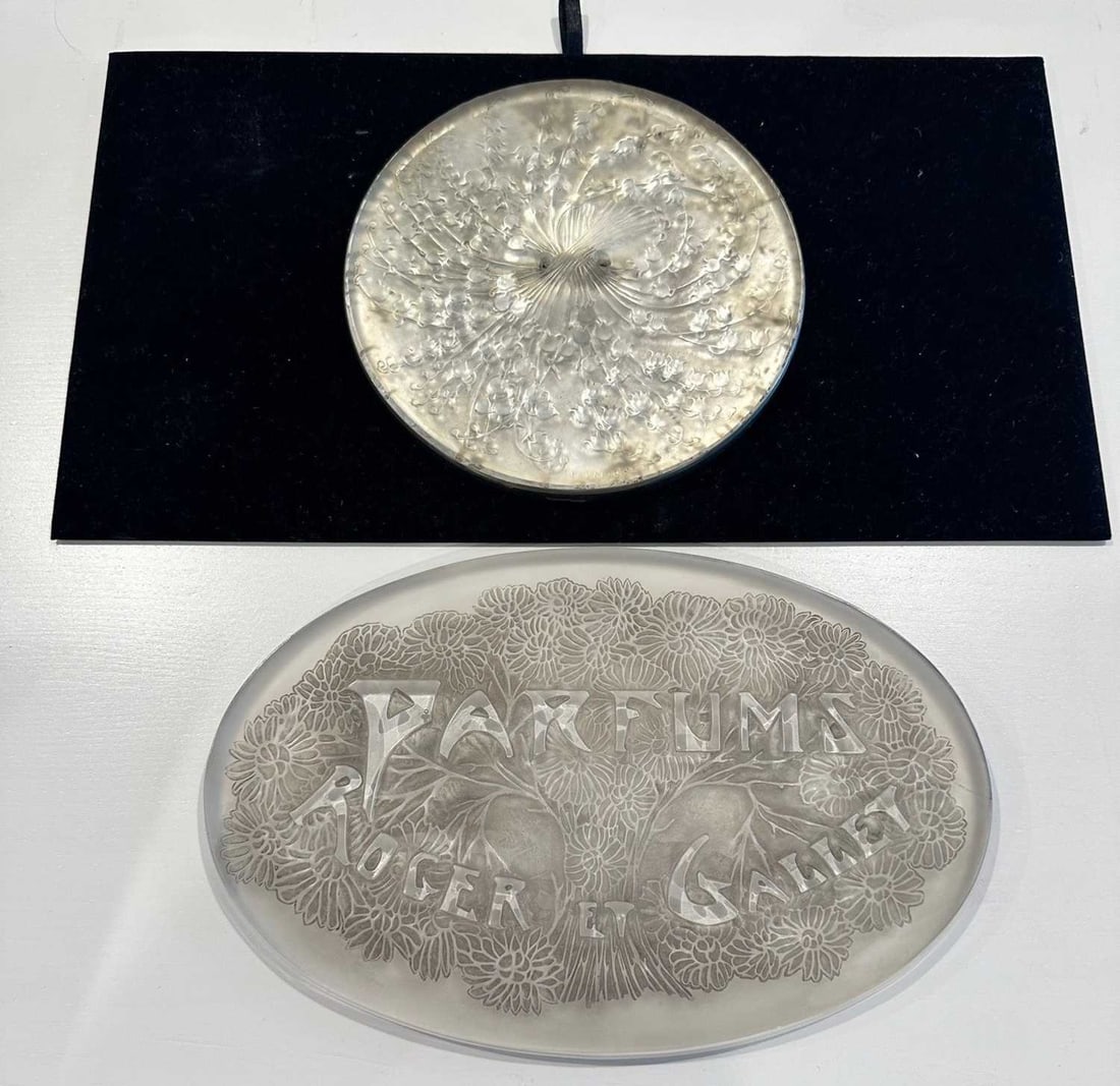 Two Lalique Molded Glass Articles: Comprising an oval PARFUMS ROGER ET GALLET advertising plaque, molded with a stylized bouquet, in colorless glass, heightened with gray enamel, unsigned, height 1/2 inches, length 10 inches, width 6 1