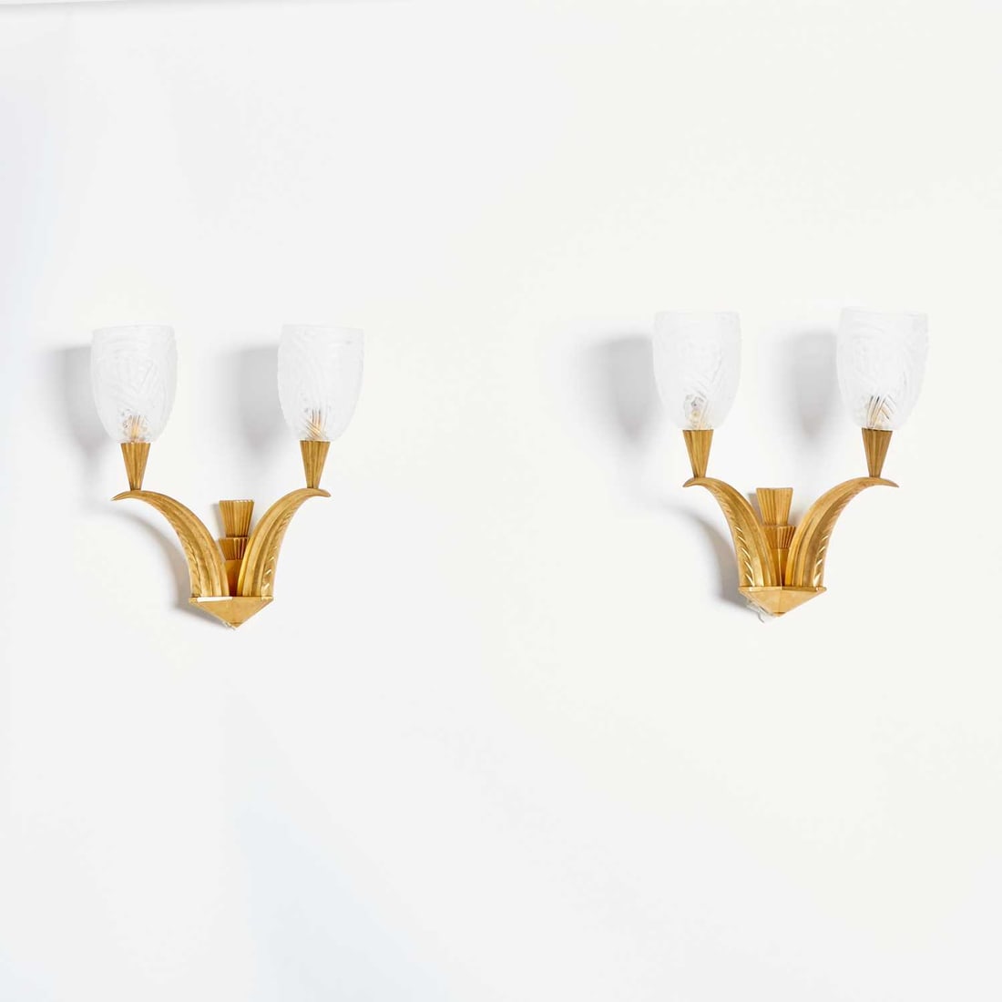 Pair of French Art Deco Gilt-Bronze and Molded Glass Two-Light Wall Sconces: Circa 1925-30 Each with a two-tiered fluted backplate fronted by upturned geometricized branches surmounted with fluted conical light sockets, with four colorless glass shades, possibly by Sabino, eac