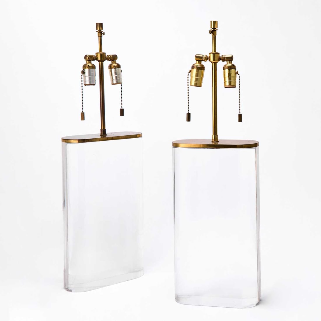 Pair of Karl Springer Lucite Lamps: Each of flattened form, with grooved sides, transparent, with metal mount, unmarked. Height of body 16 1/2 inches, width 9 inches.