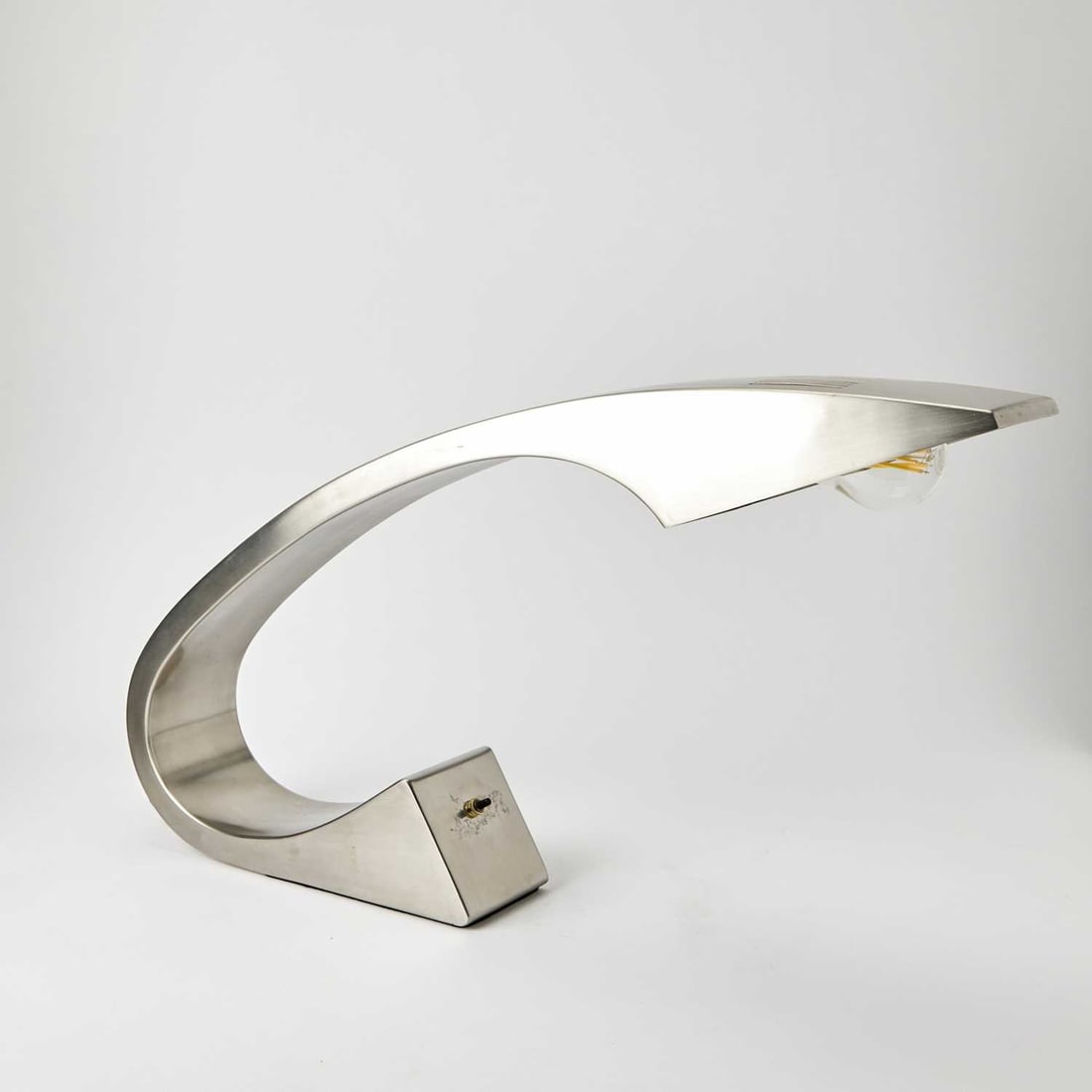 Fase Mid-Century Design Stainless Steel “Impala” Table Lamp: 1970s Of curved form with an integral base and shade, unmarked. Height 14 3/4 inches, length 26 1/2