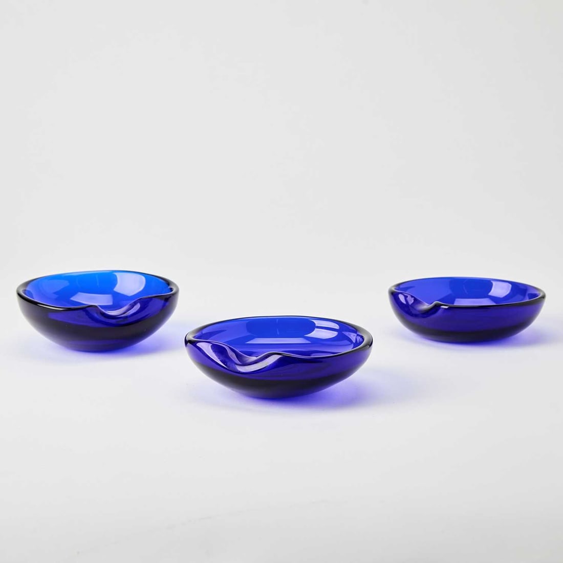 Three Elsa Peretti for Tiffany & Co. Hand-Blown Glass Small "Thumbprint" Bowls: Made in Italy, 1980s Each in transparent cobalt blue colored glass, inscribed ELSA PERETTI for Tiffany. Height 1 7/8 inches, length 5 inches.