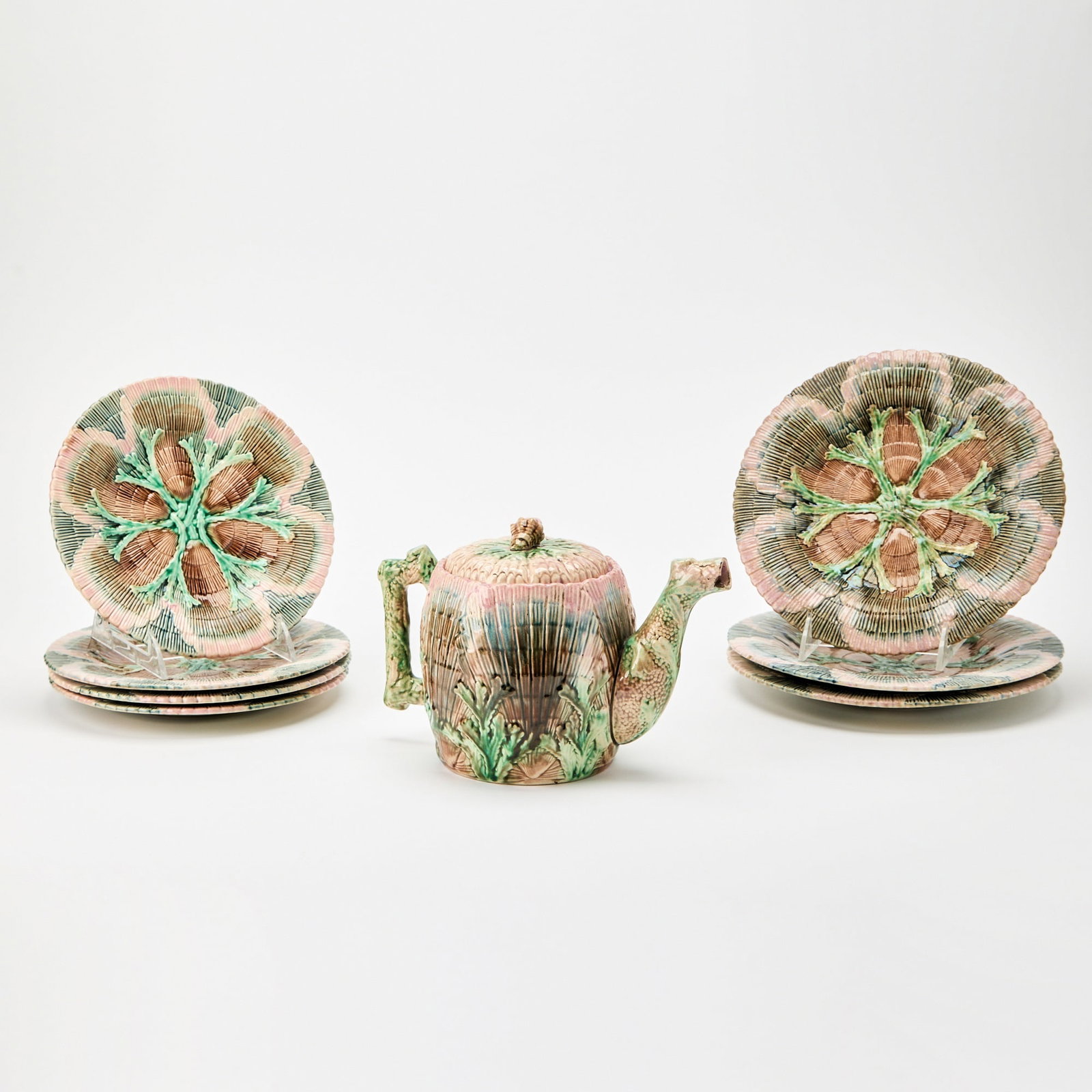 Griffen, Smith & Hill Etruscan Majolica Shell and Seaweed Pattern Partial Tea Service: Late 19th century Comprising a teapot, height 6 inches; and seven plates in two sizes, diameter of largest 9 3/4 inches; each molded with leaves and sea vegetation.