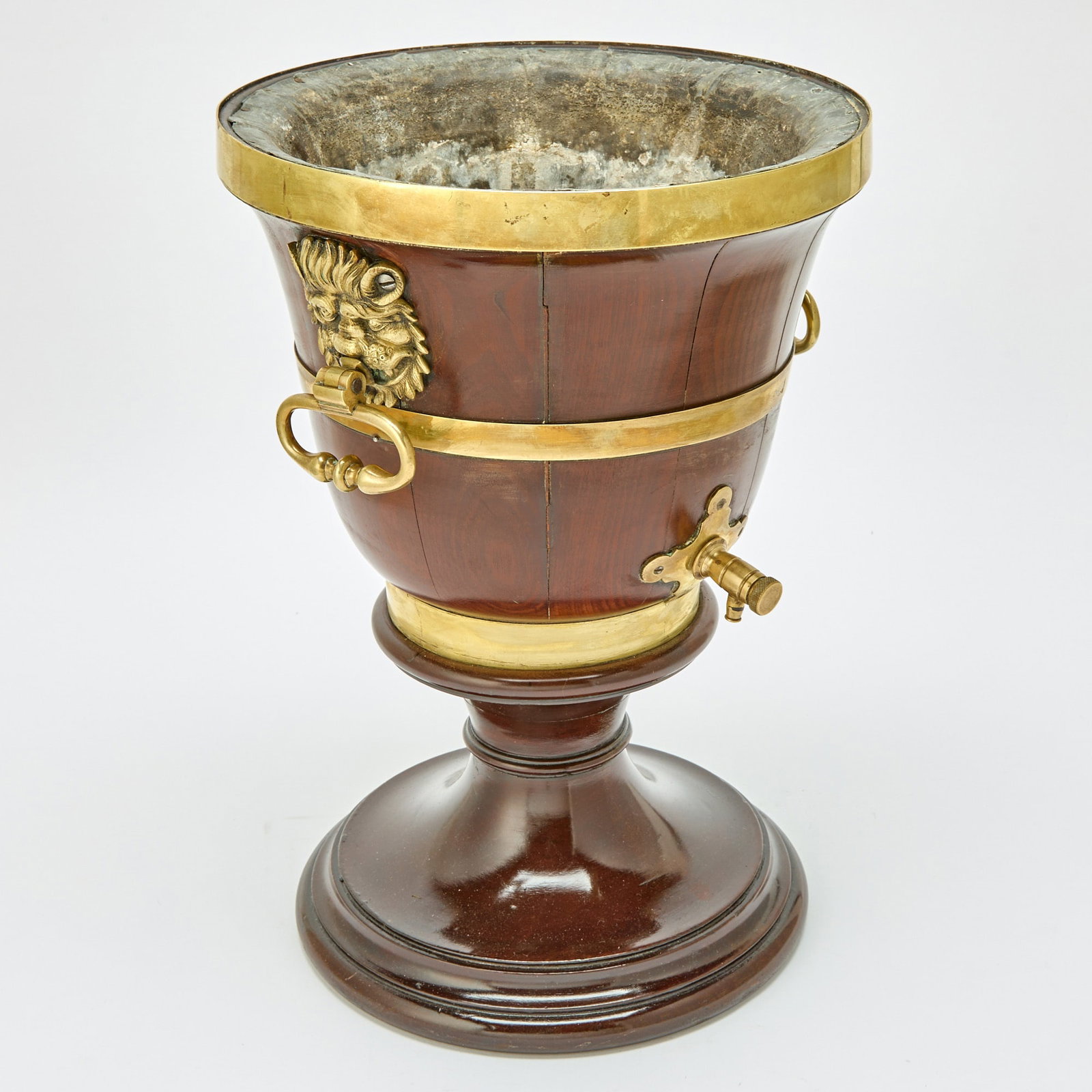 William IV Brass-Mounted Mahogany Cistern: Mid 19th century Of urn form with brass lion's head and ring mask handles, on a banded socle and circular foot. Height 17 3/4 inches, diameter 12 1/4 inches.