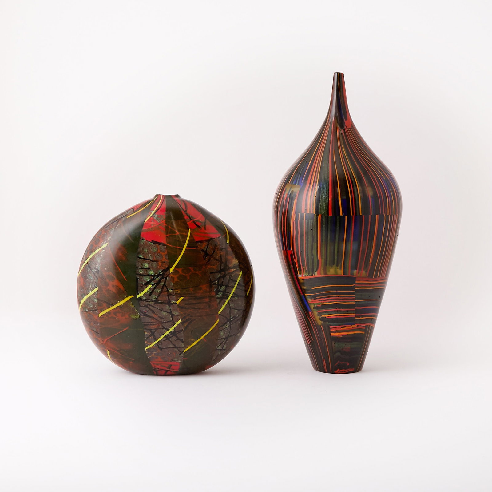 Two Michele Burato Blown Glass Vases: 1999 Comprising an example of tapering ovoid form, with multicolored striped decoration, and an example of flattened globular form, multicolored with varied decoration, each signed and dated. Height