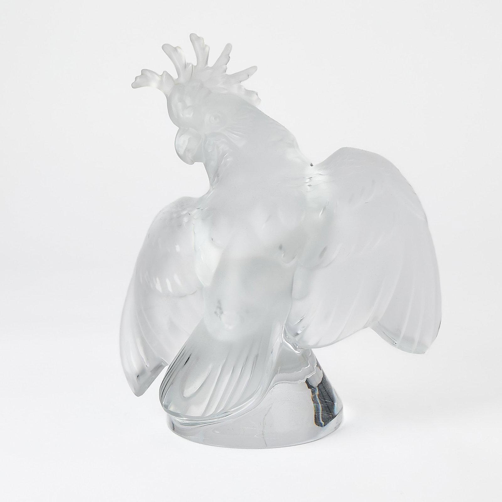 Lalique Molded Glass Figure of a Cockatoo: Late 20th/early 21st century Modeled with outspread wings and perched on a domed base, in colorless glass, satin and glossy finish, engraved Lalique France. Height 11 3/4 inches, width 10 1/8 inches.