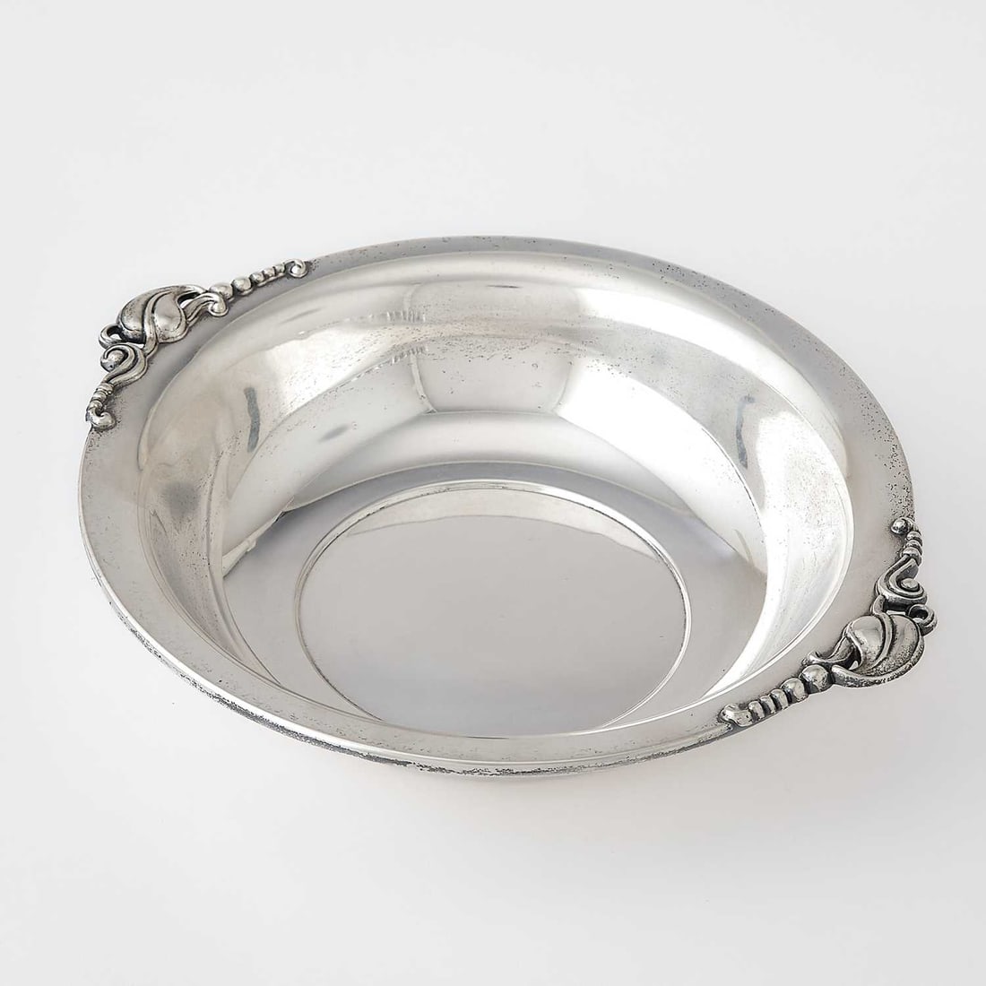 American Sterling Silver Bowl: Quaker Silver Co., mid 20th century Circular with applied stylized blossom-form handles. Length over handles 9 3/4 inches, approximately 7 ounces.
