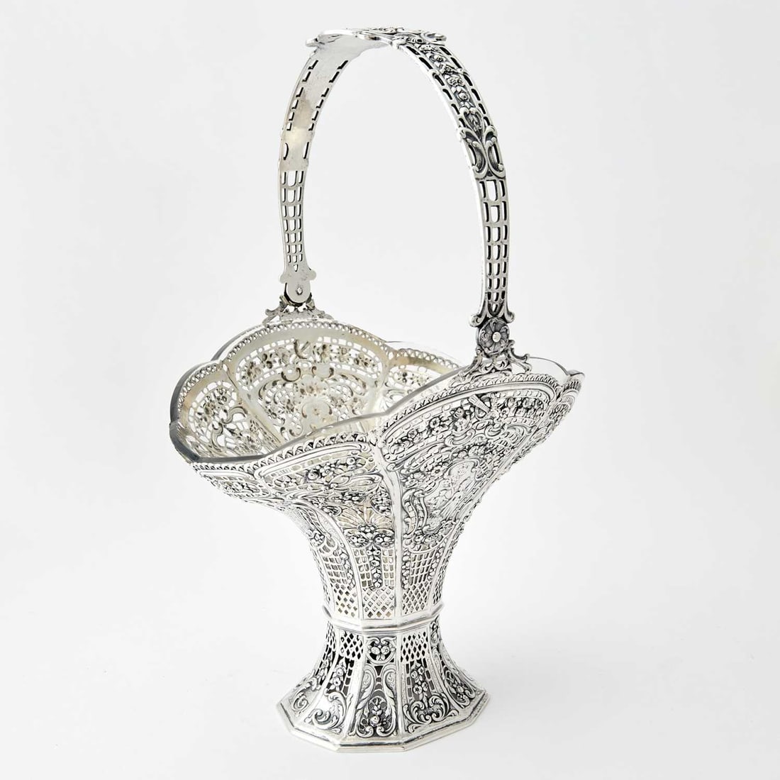 Continental Silver Centerpiece Basket: Late 19th/early 20th century The flaring body with pierced panels of flowers and lattice, the overhead swing handle with cupid's bow and arrows, with a glass liner. Height over handle 15 1/2 inches, l
