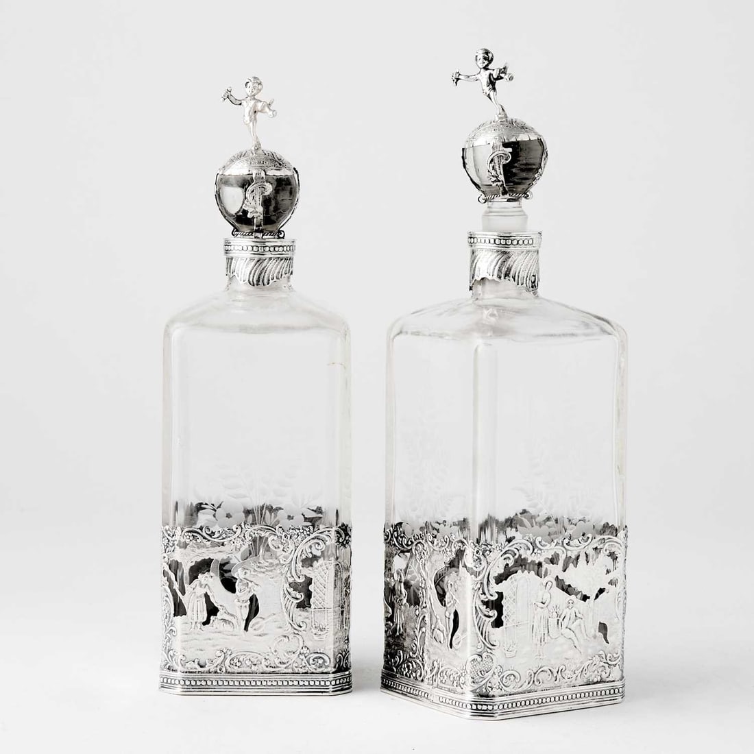 Pair of Dutch Silver Mounted Etched Glass Decanters: Late 19th/early 20th century Each square bottle with repeating band of figural scenes. Height 8 3/4 inches.