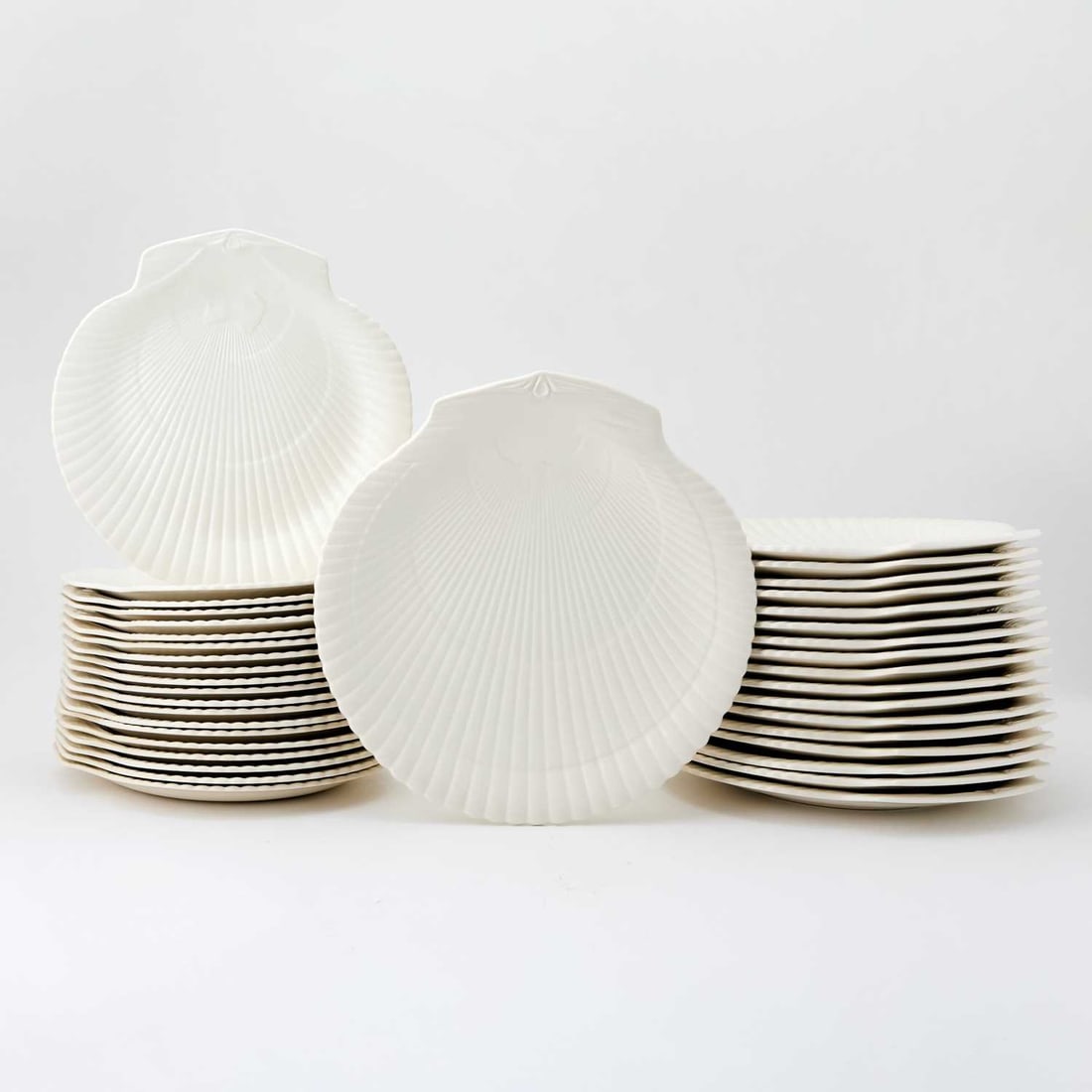 Set of Forty-Four Wedgwood of Etruria & Barlaston Porcelain "Moonstone (Cream)" Pattern Plates: Each shell-shaped, in two sizes, comprising: Eighteen dinner plates, width 10 3/4 inches Twenty salad plates, width 9 1/8 inches (38)