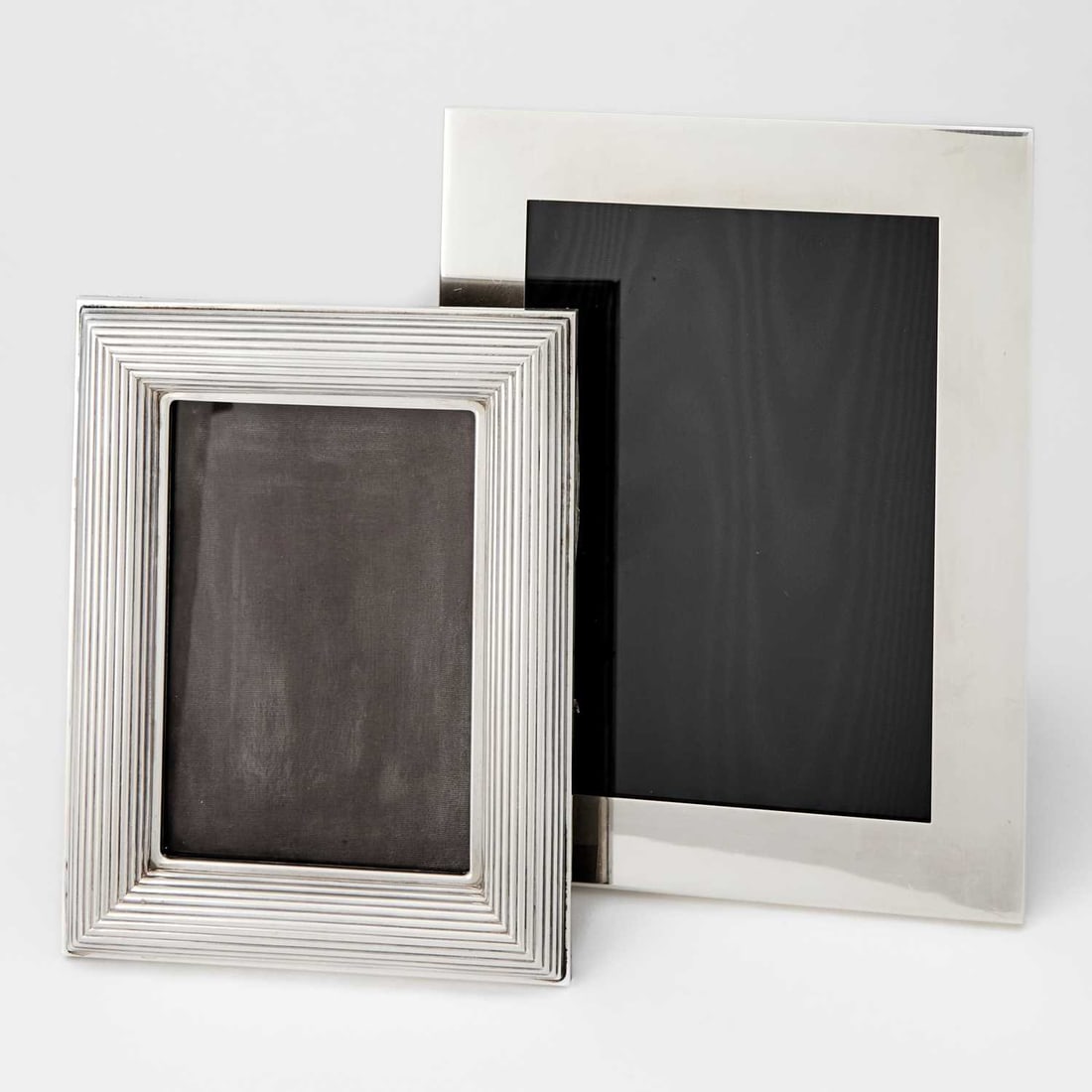 Tiffany & Co. Sterling Silver Photo Frame and a Cartier Sterling Silver Photo Frame: Late 20th century The Tiffany & Co. example with plain border, height 9 inches, width 7 inches; the Cartier example with reeded border, height 7 1/2 inches, width 5 3/4 inches.