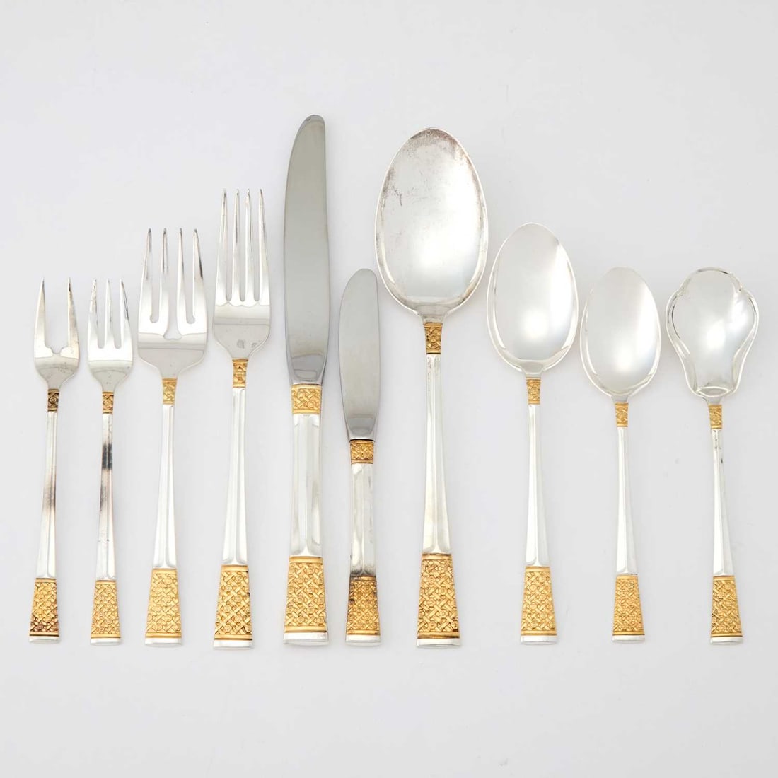 Lunt Sterling Silver "Golden Columbine" Pattern Flatware Service: Mid 20th century Comprising: Twelve dinner forks Twelve salad forks Six cocktail forks Twelve dinner knives Twelve butter knives Twelve dessert spoons Twelve teaspoons Two sugar spoons Cake serve