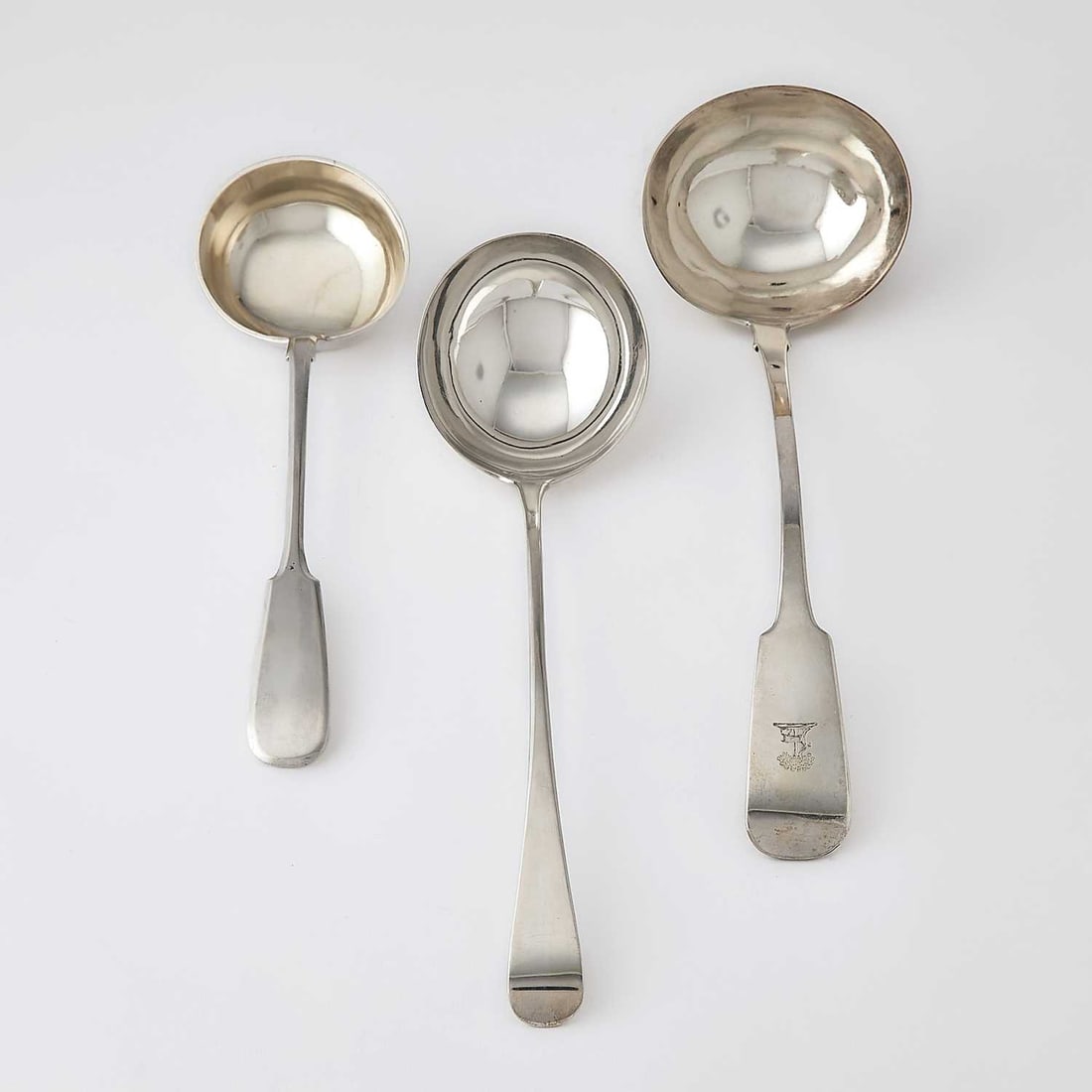 Three Silver Soup Ladles: Comprising a Russian example, length 11 1/2 inches; Irish George IV example, length 14 inches; and a Georgian example, length 13 inches, total approximately 20 ounces.