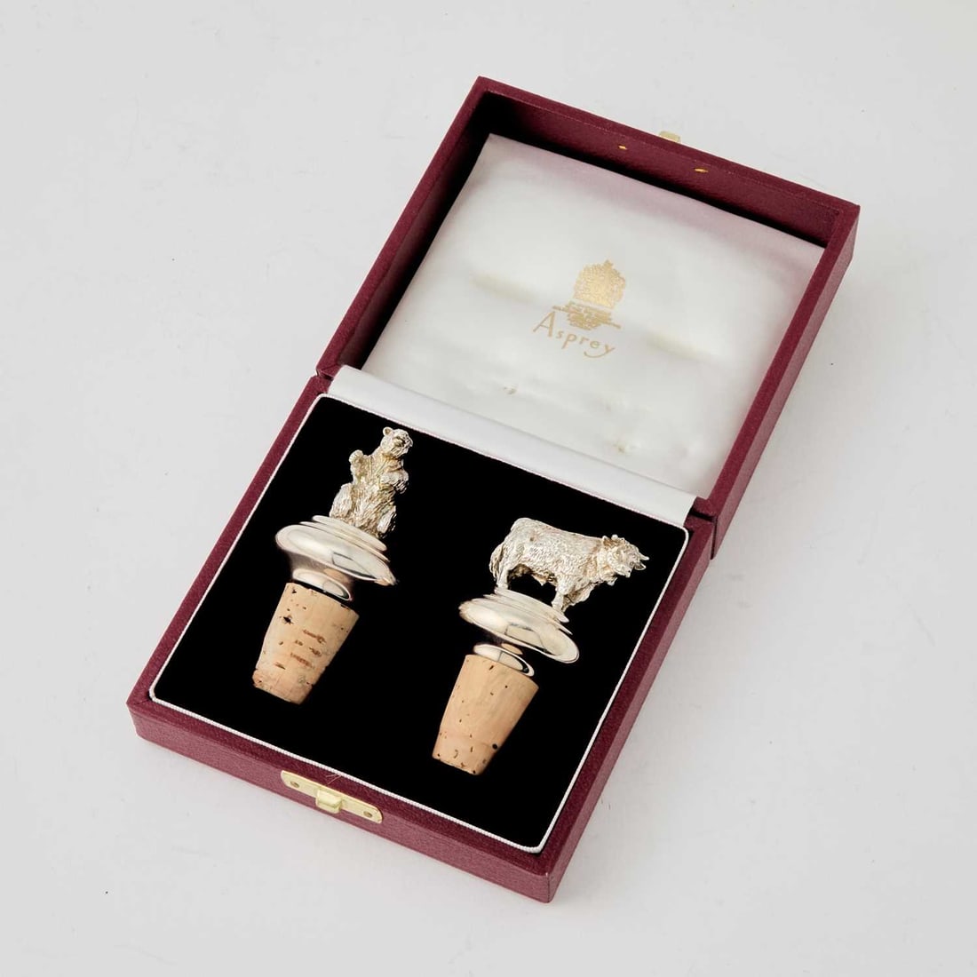 Cased Pair of Asprey Sterling Silver "Bull and Bear" Bottle Stoppers: London, 1994 Height of larger 3 1/4 inches, weighted. Generally good condition overall; one cork loose; good detail to casting