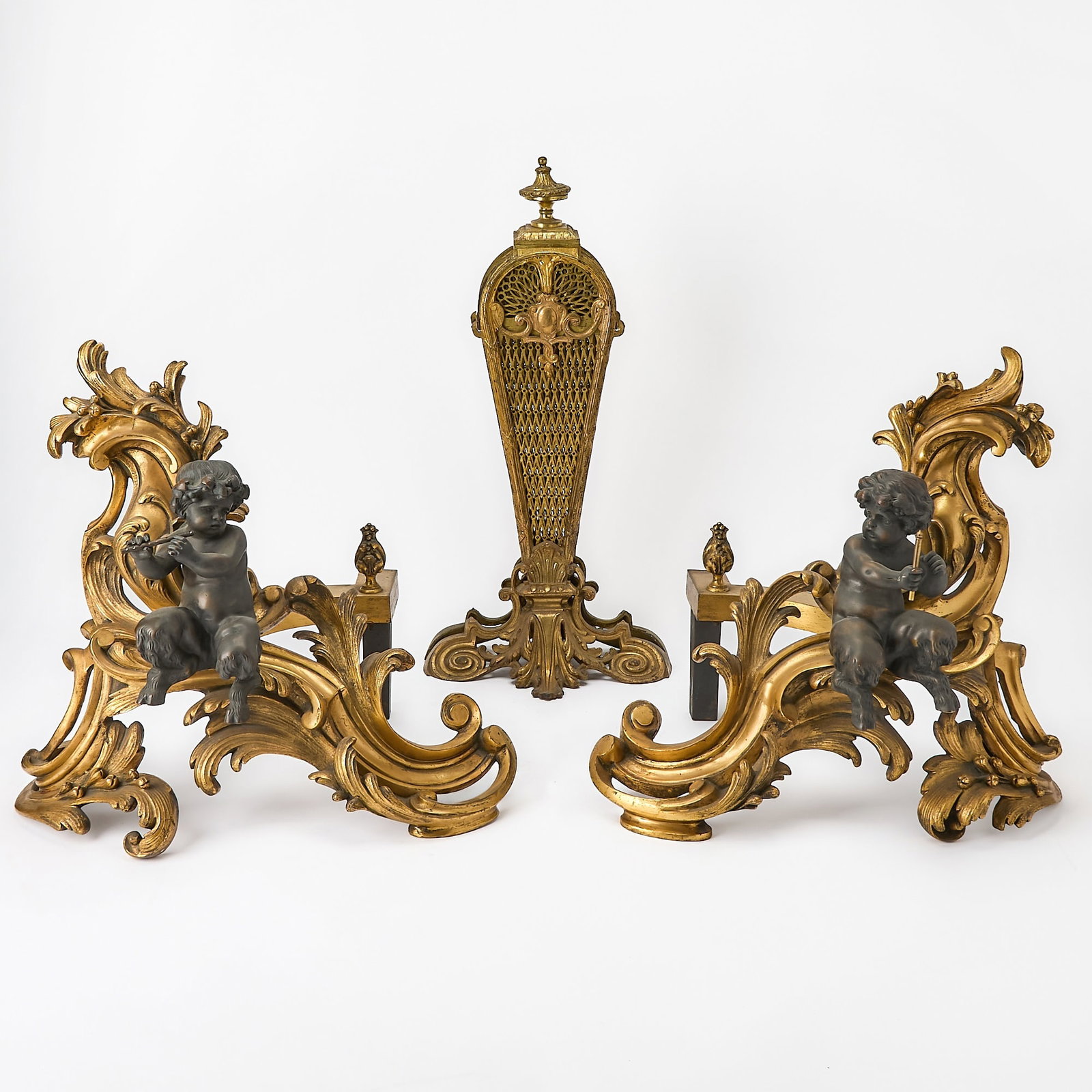 Pair of Rococo Style Gilt and Patinated Bronze Chenets: 19th century Together with a Brass Peacock Folding Firescreen. Each in the form of seated satyrs, height 16 1/2 inches, width 20 inches, depth 12 1/2 inches Rubbing to gilt elements.