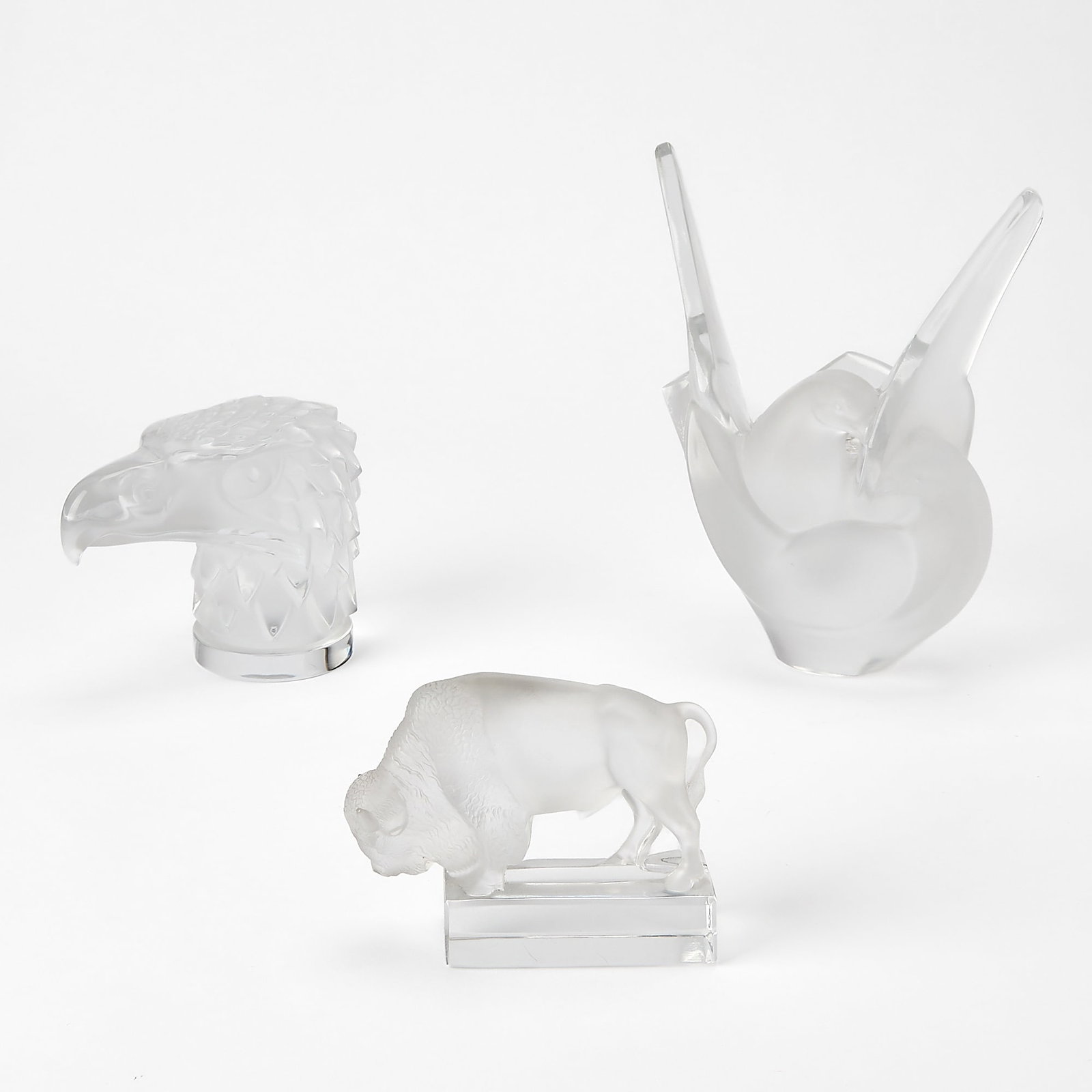 Three Lalique Glass Figures: 20th century Comprising 'Sylvie' flower frog, 'Eagle' and 'Bison', with etched maker's mark. Largest 8 1/2 inches, width 6 3/4 inches Bison with small loss to top of left horn.