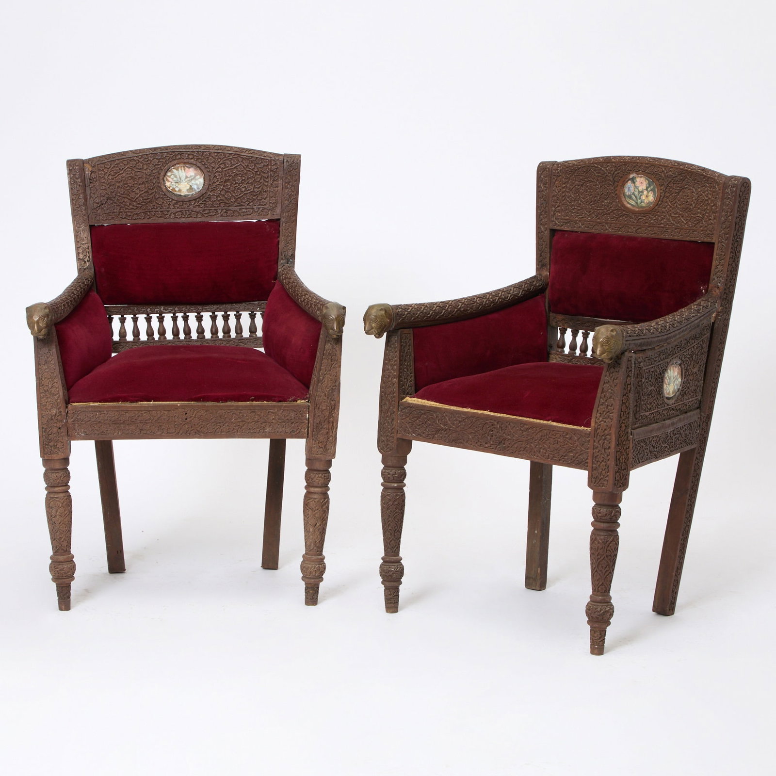 Pair of Indian Mughal Style Upholstered Armchairs: 19th century Each intricately carved with arms ending with brass lion head terminals, the back and sides with oval floral paintings. Height 36 inches, width 24 inches, depth 19 inches